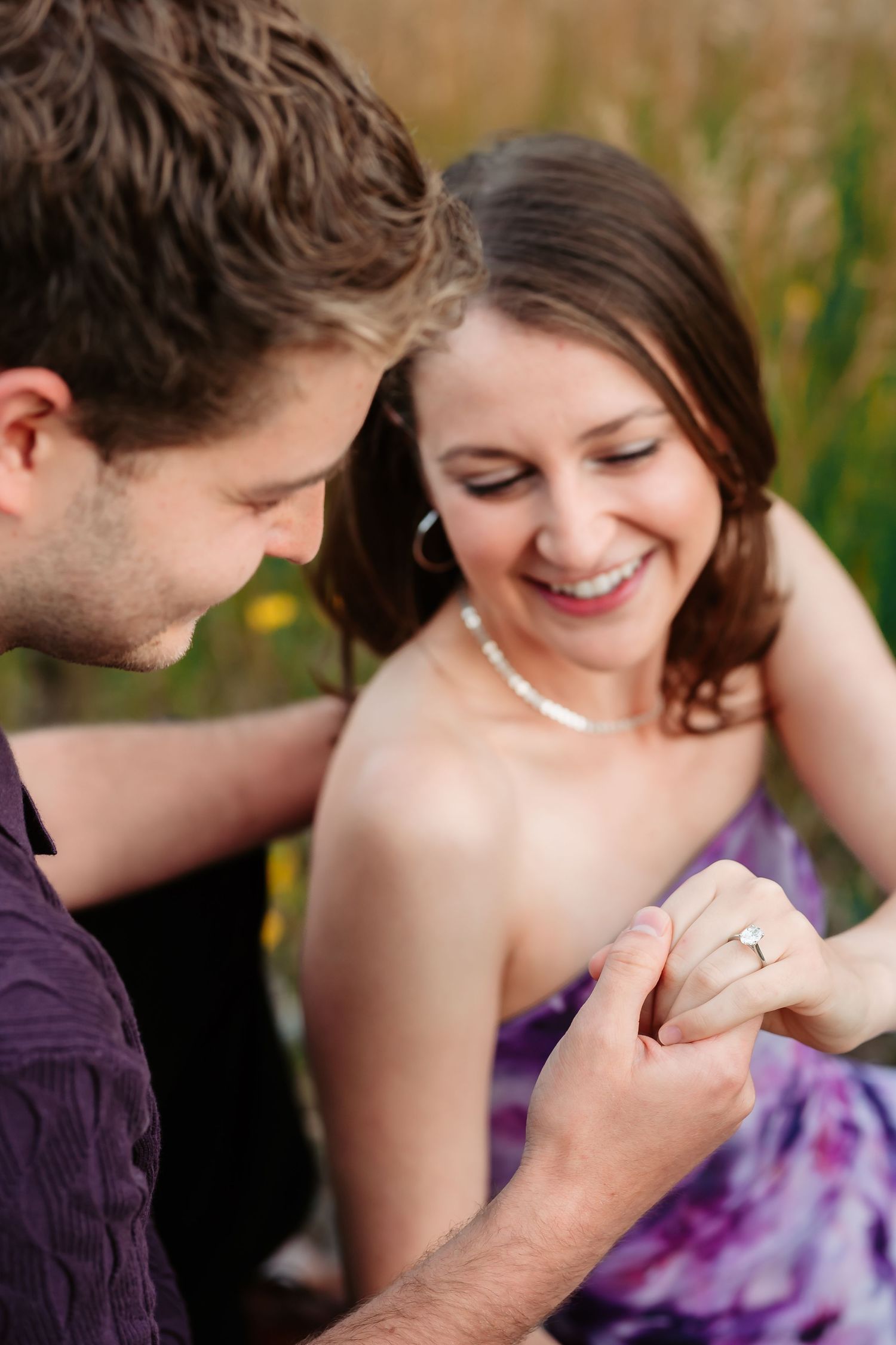 Close-up of a touching moment between a couple in purple attire.