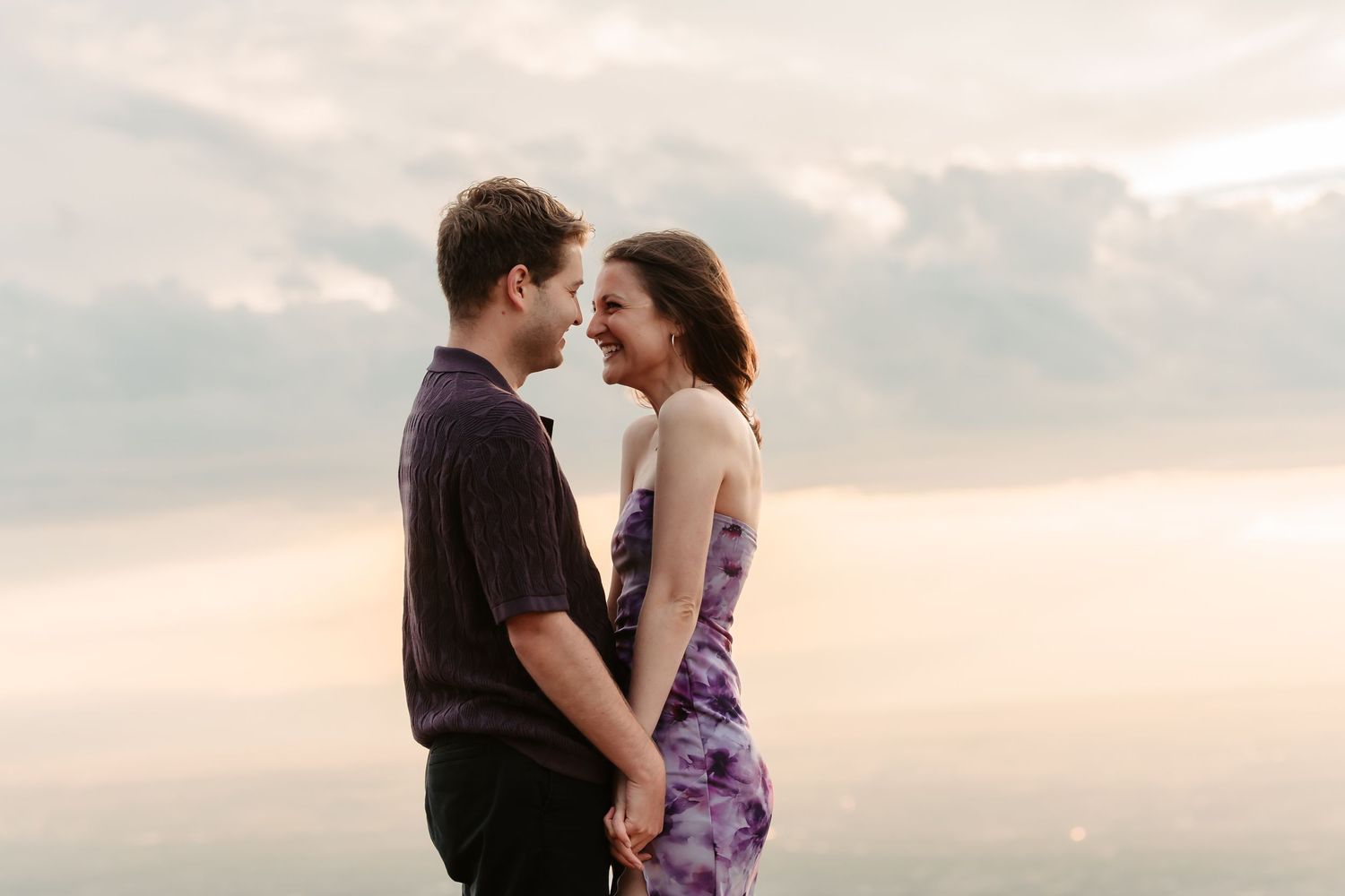An intimate romantic moment shared on a mountain peak during sunset.