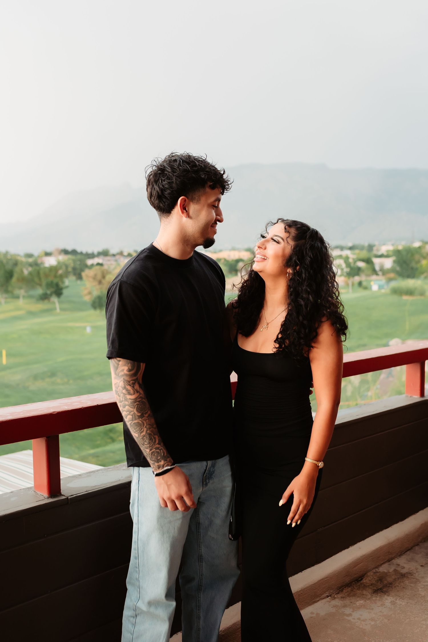 A joyful couple shares a laugh together on a balcony overlooking mountain views.