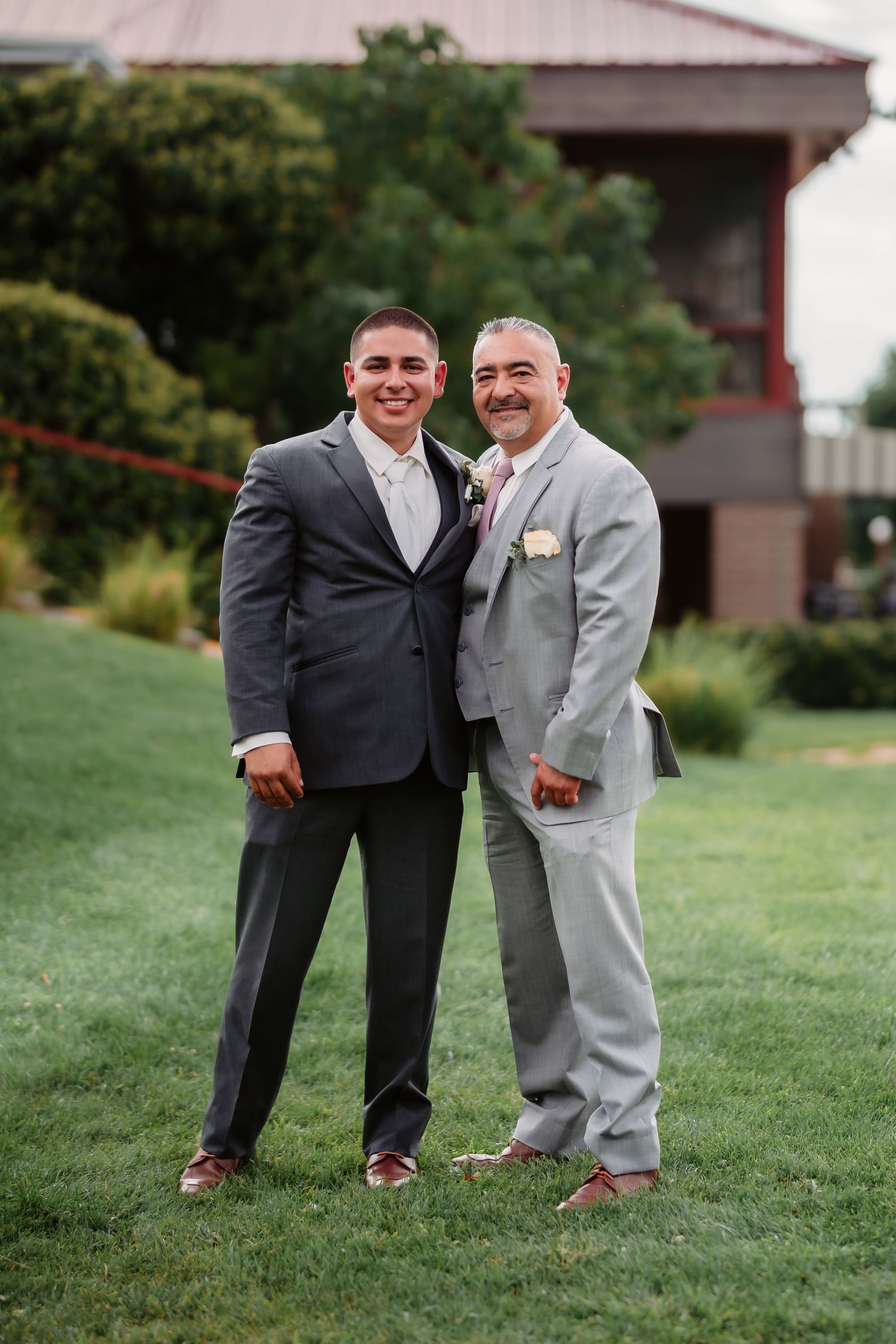A series of four photos showing two people in formal suits posing together on a grassy lawn.