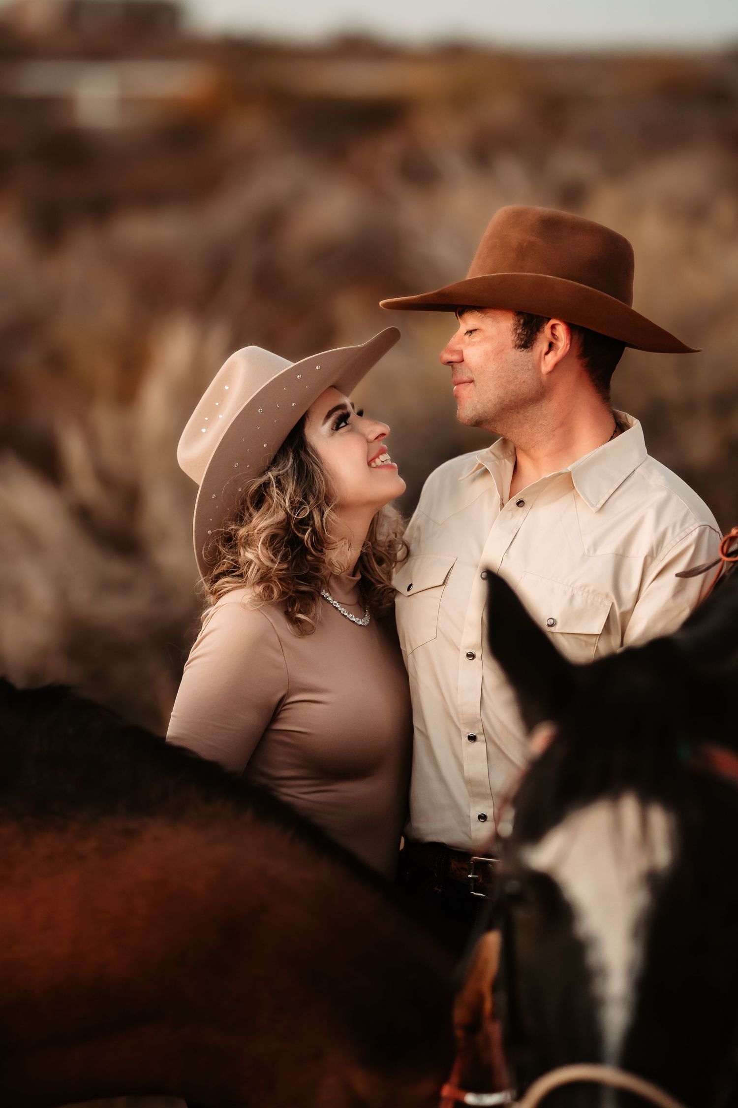 A romantic western-themed couple in cowboy hats share intimate moments against a rustic brown background.