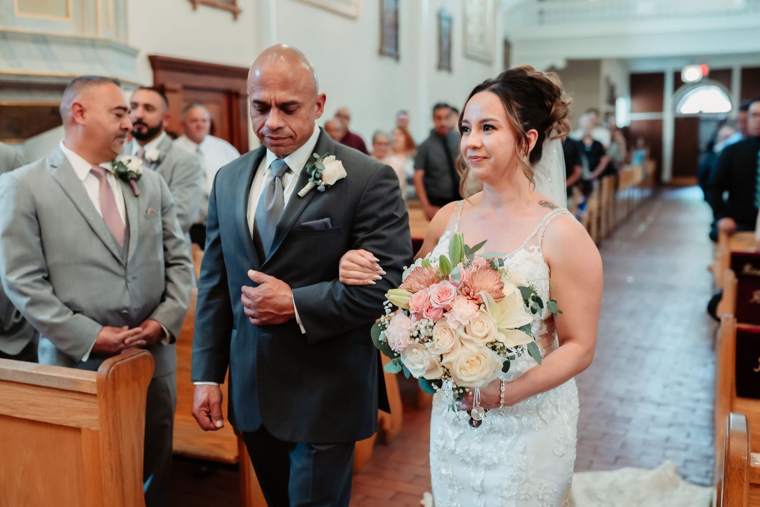 Intimate wedding ceremony in progress with guests seated in wooden church pews.