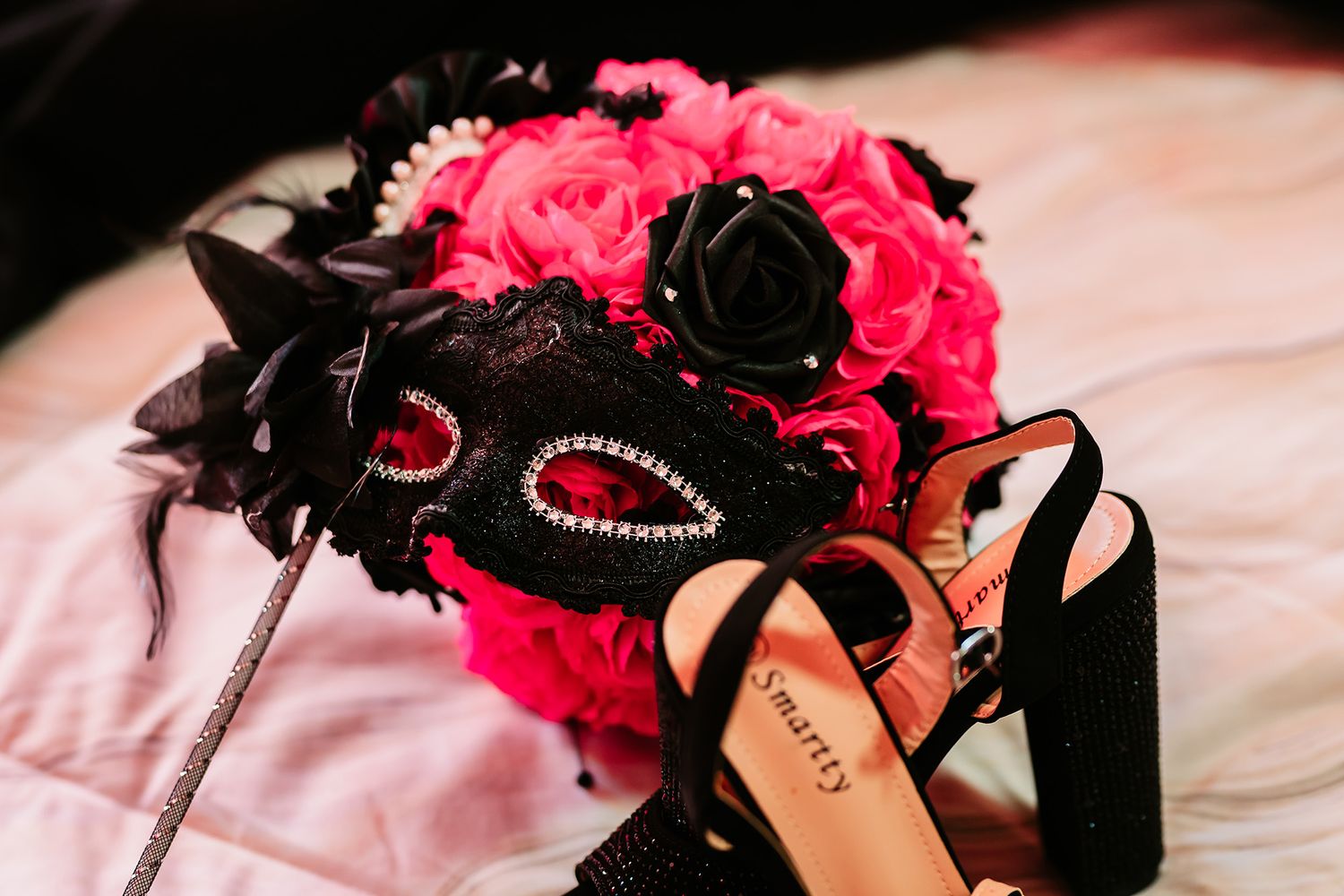 Pink roses and black accessories arranged with pearls and formal wear items.
