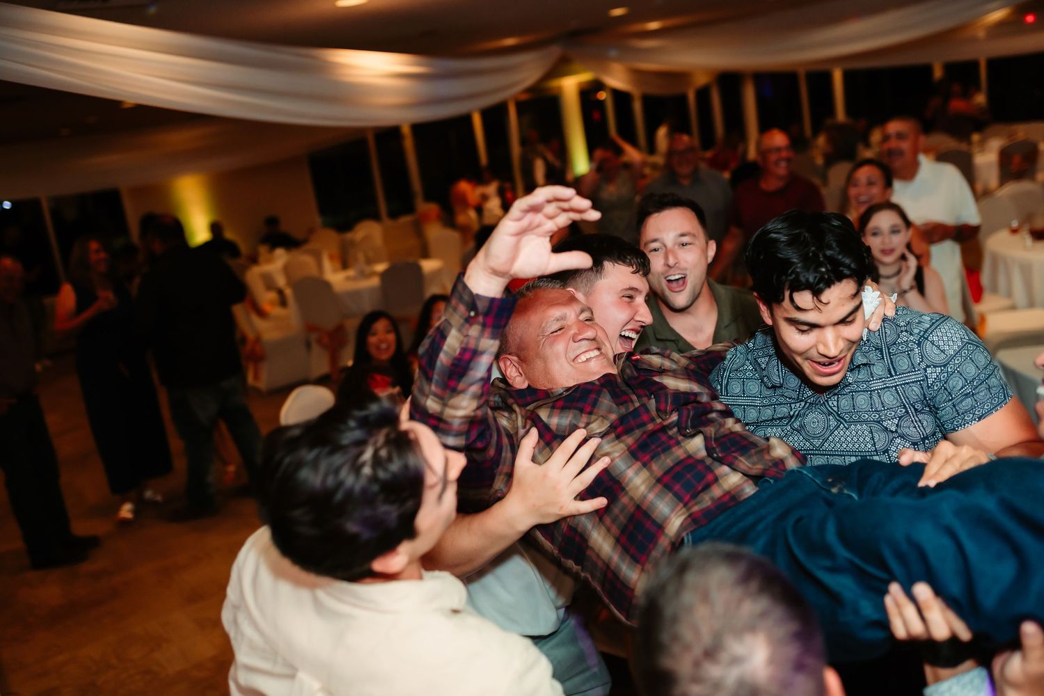Lively dance floor moment at wedding reception with guests celebrating.
