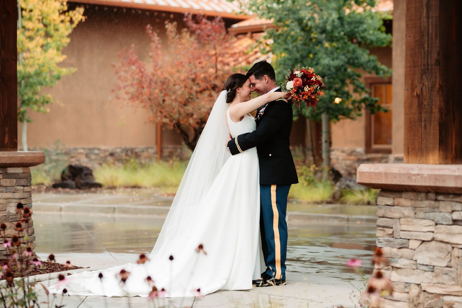 A romantic couple shares a tender moment on stone steps surrounded by autumn foliage and red berries.