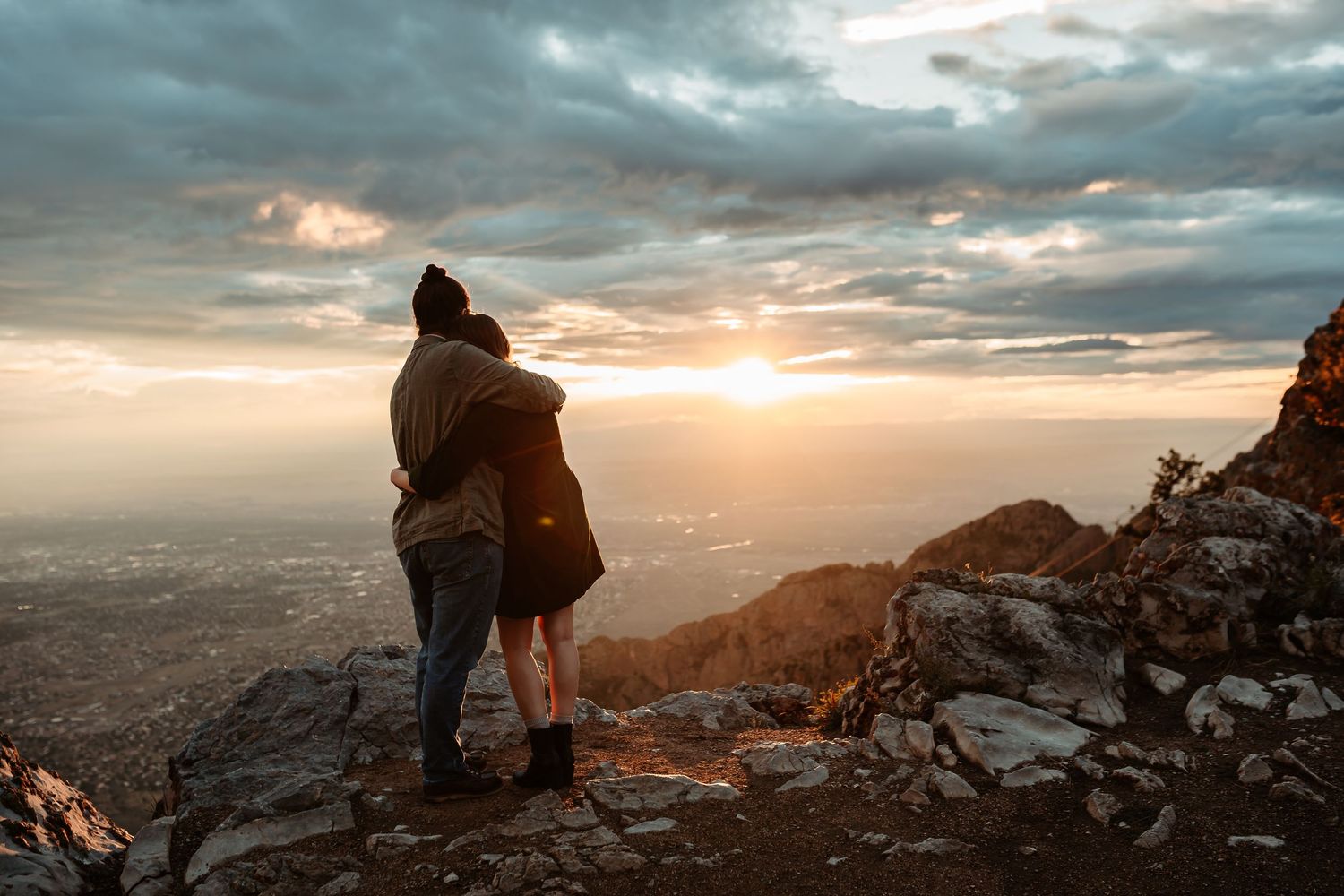 A series of mountain summit photos showing hikers watching dramatic sunsets over rugged peaks and valleys.