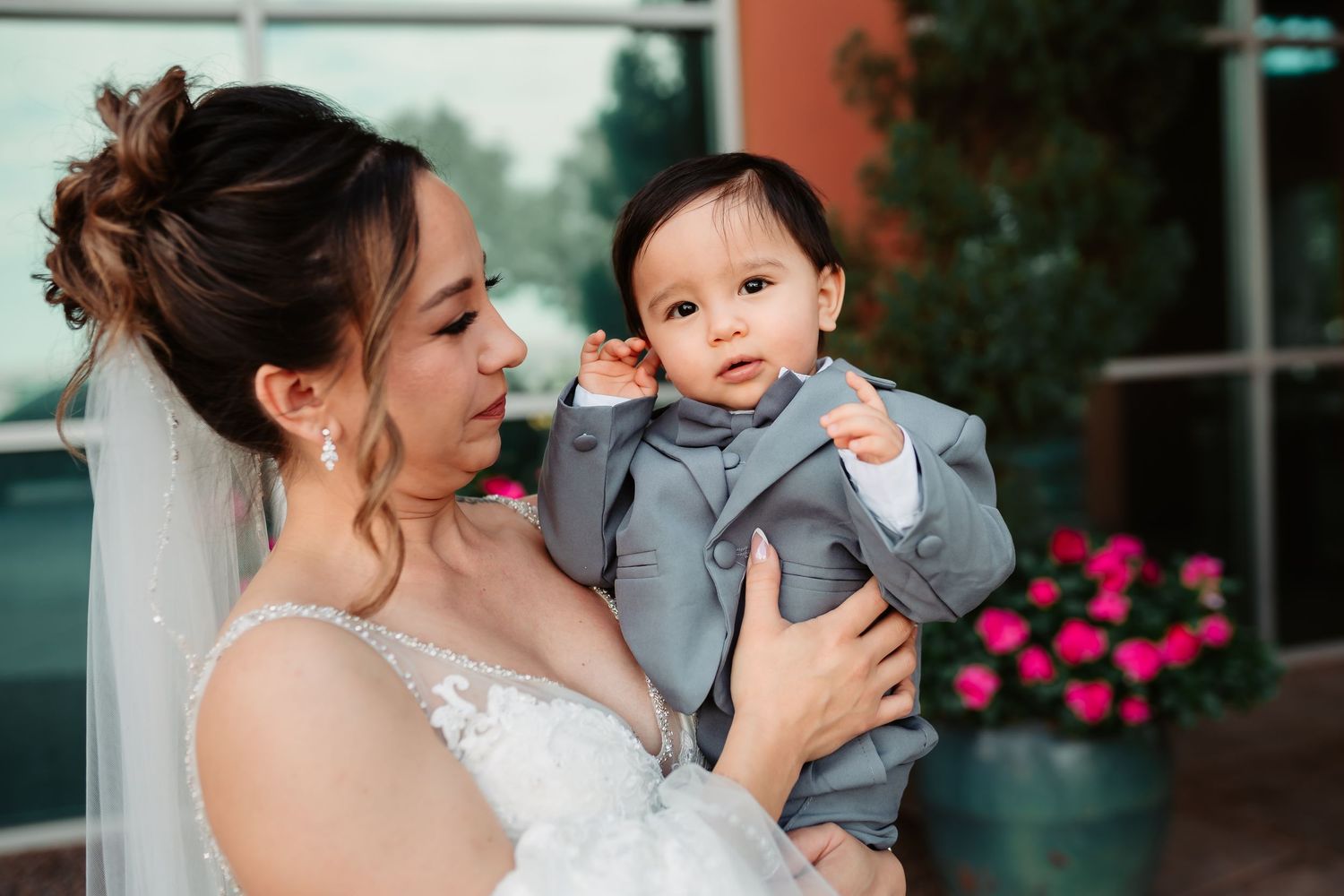 Wedding photos showing tender moments between a bride and small child at an outdoor venue with pink flowers in background.
