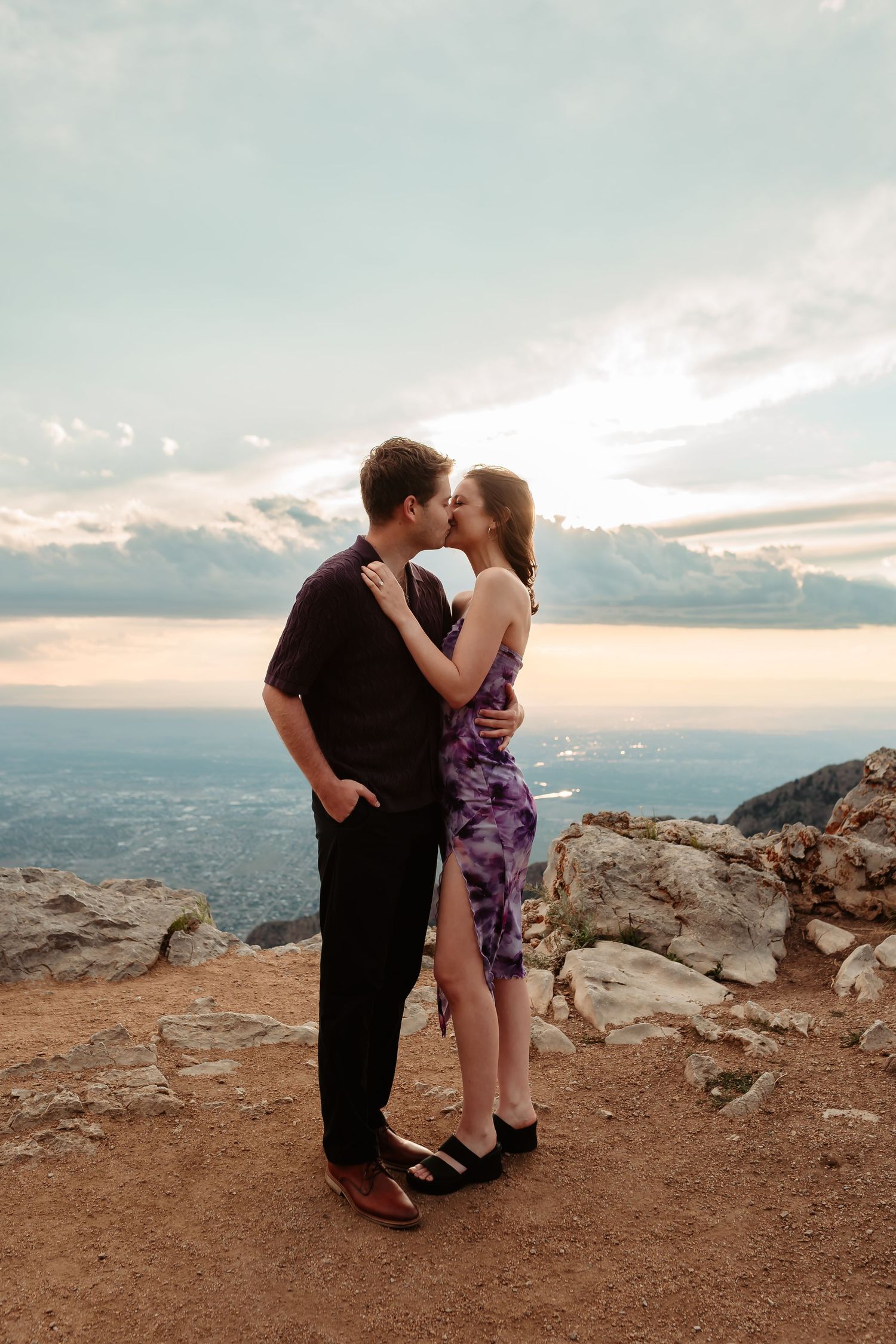 A couple sharing tender moments on a mountain overlook with a scenic valley view.