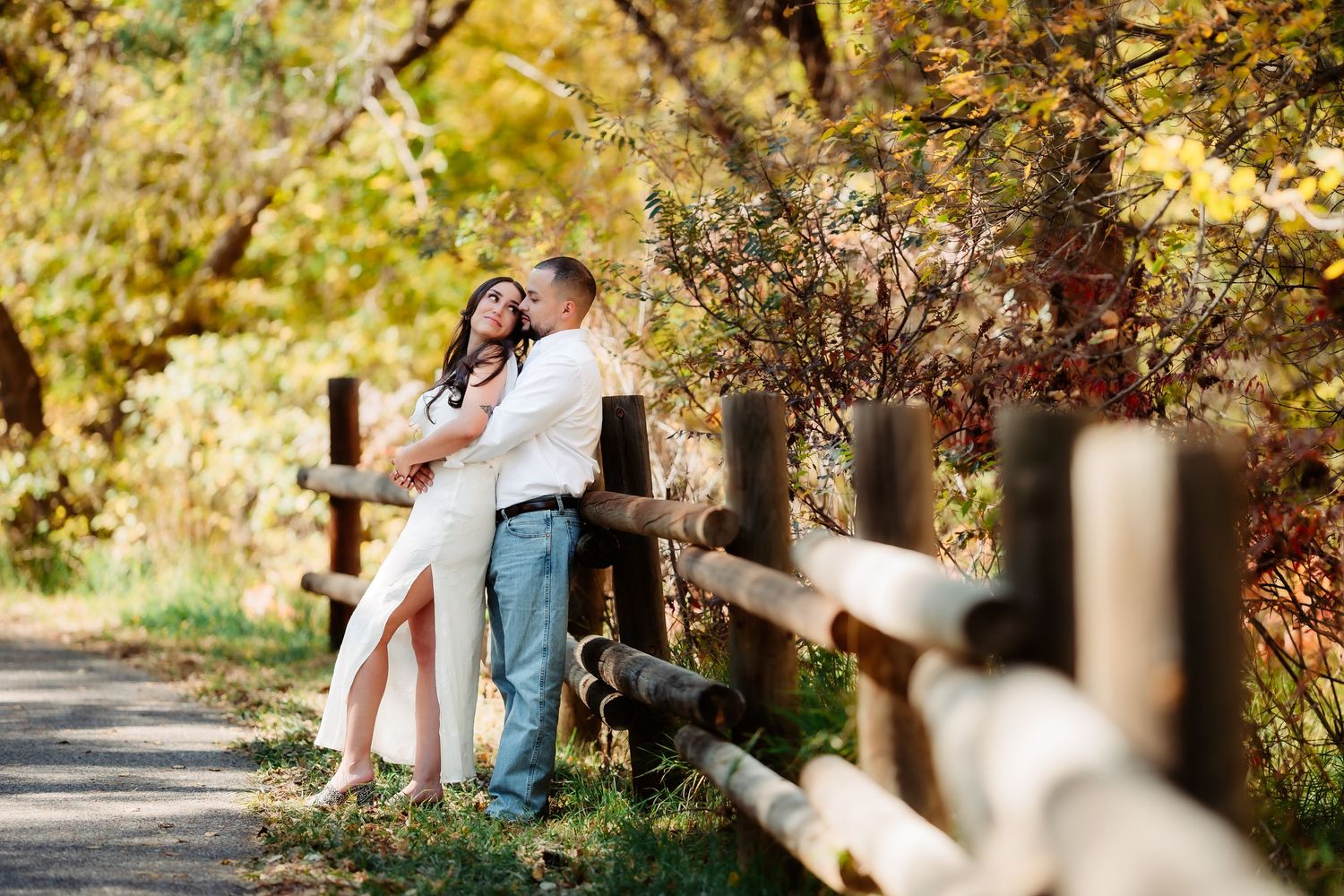Couple sitting together on a rustic wooden bench surrounded by fall foliage in a peaceful park setting.