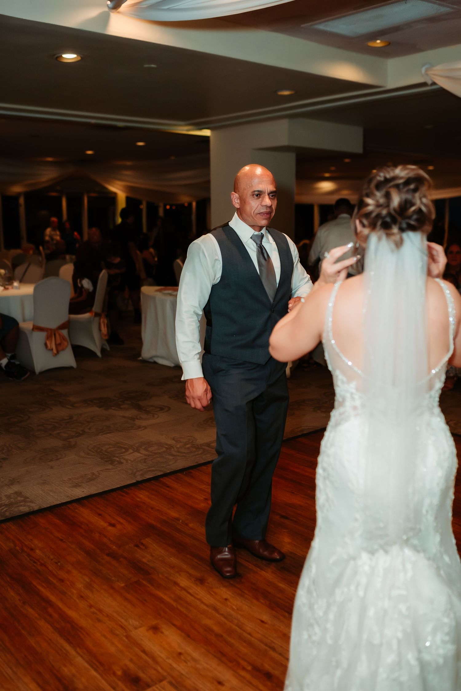 Newlyweds dancing together on a wooden dance floor at their wedding reception.