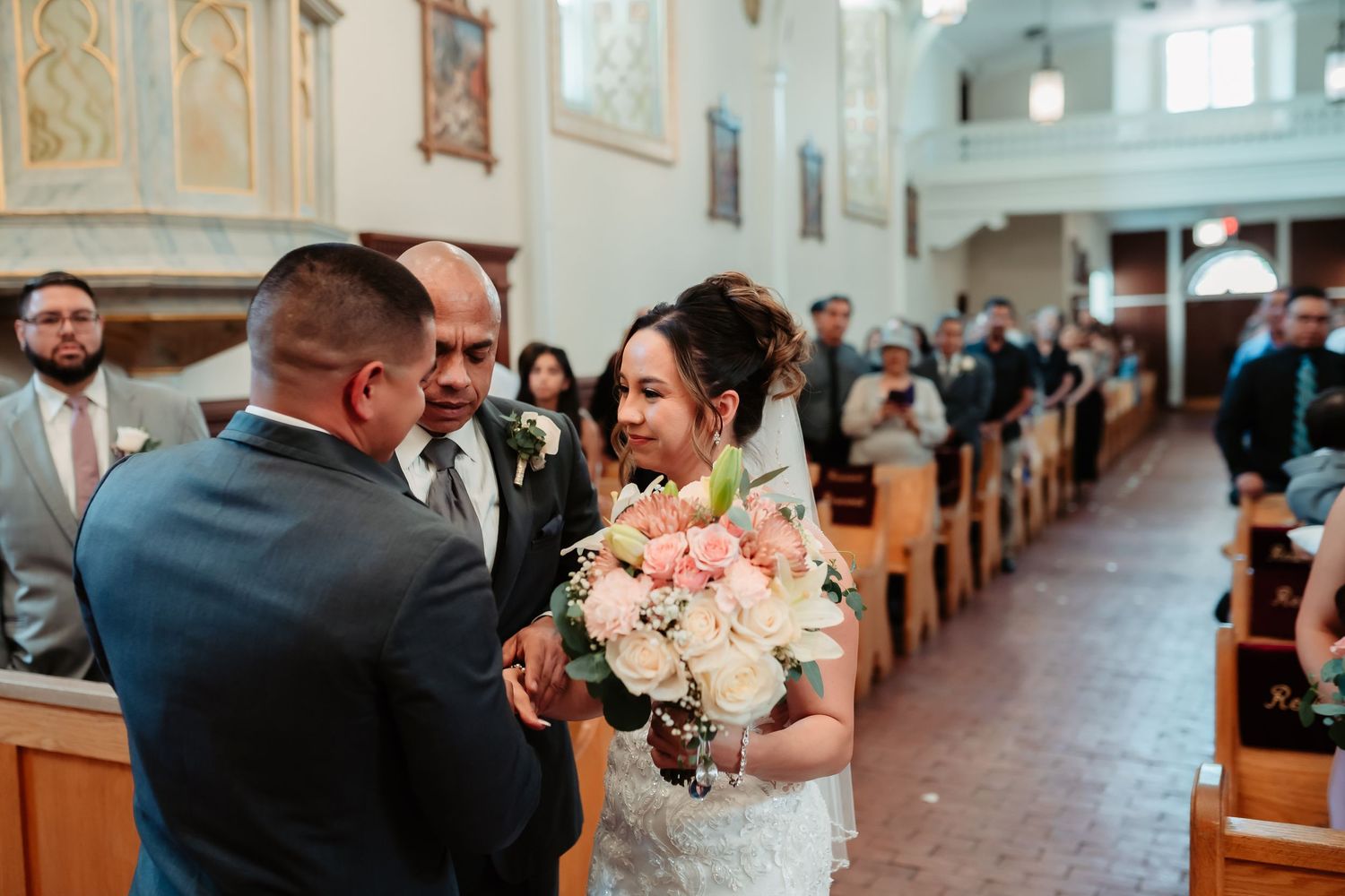 Interior of traditional church with wooden pews and white walls during wedding ceremony.