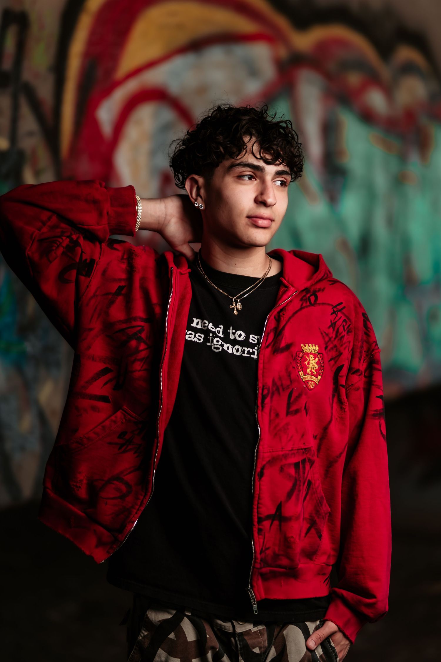 Fashion portrait against street art wall featuring red zip-up jacket and black t-shirt.