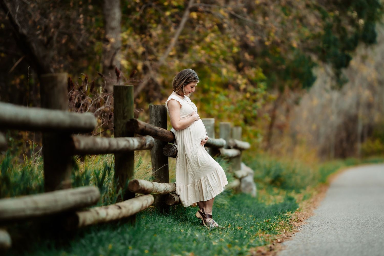 A couple sits on a rustic wooden bridge surrounded by autumn foliage in a romantic outdoor setting.