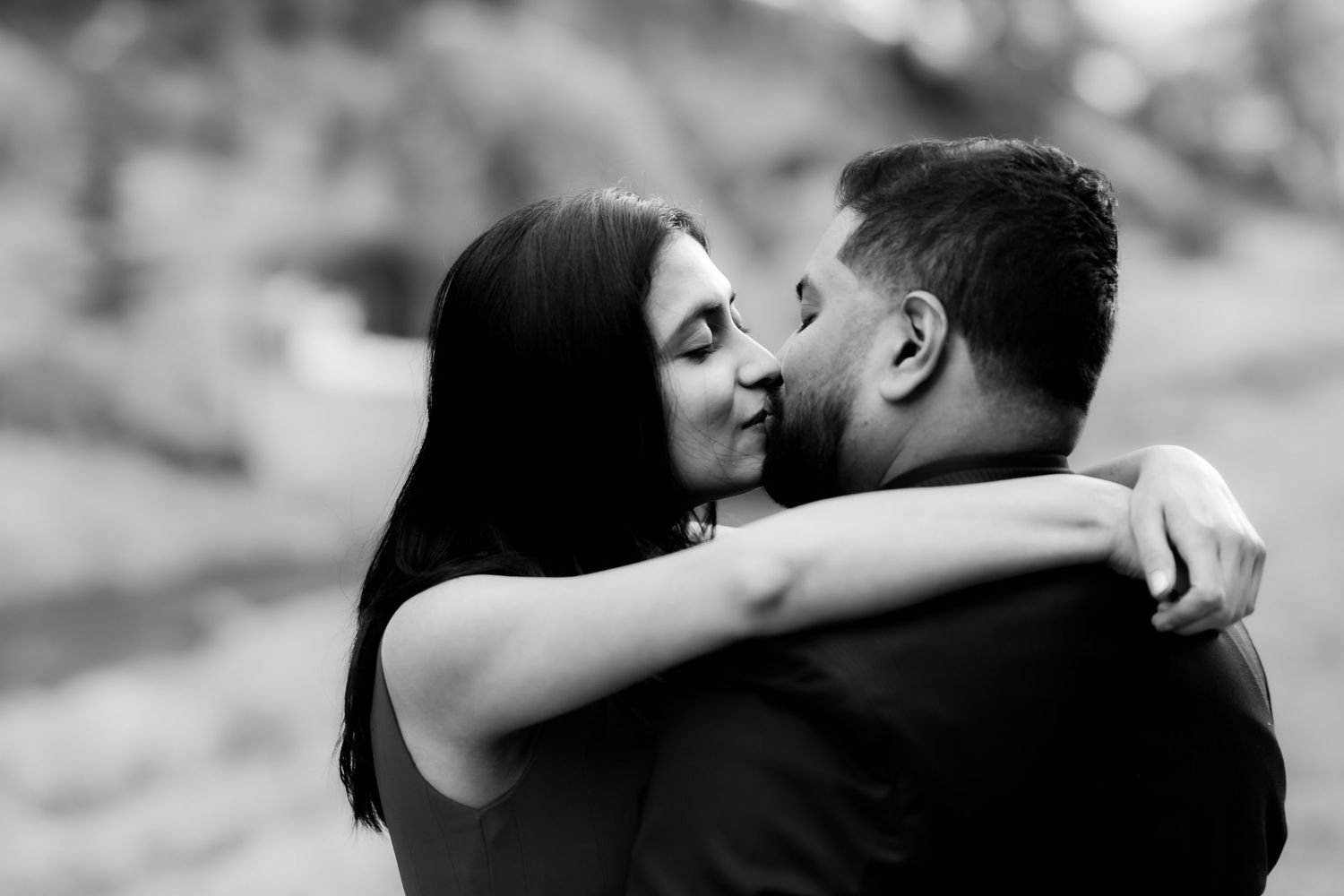 An intimate close-up black and white portrait of a couple sharing a romantic embrace.