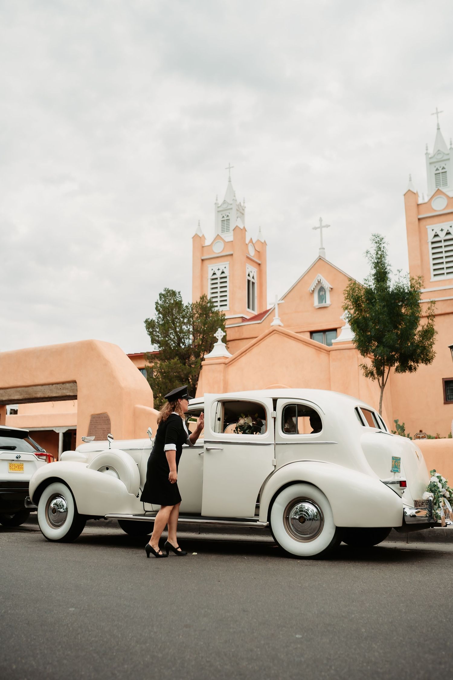 Wedding photo sequence featuring a vintage white car parked outside a pink adobe church.