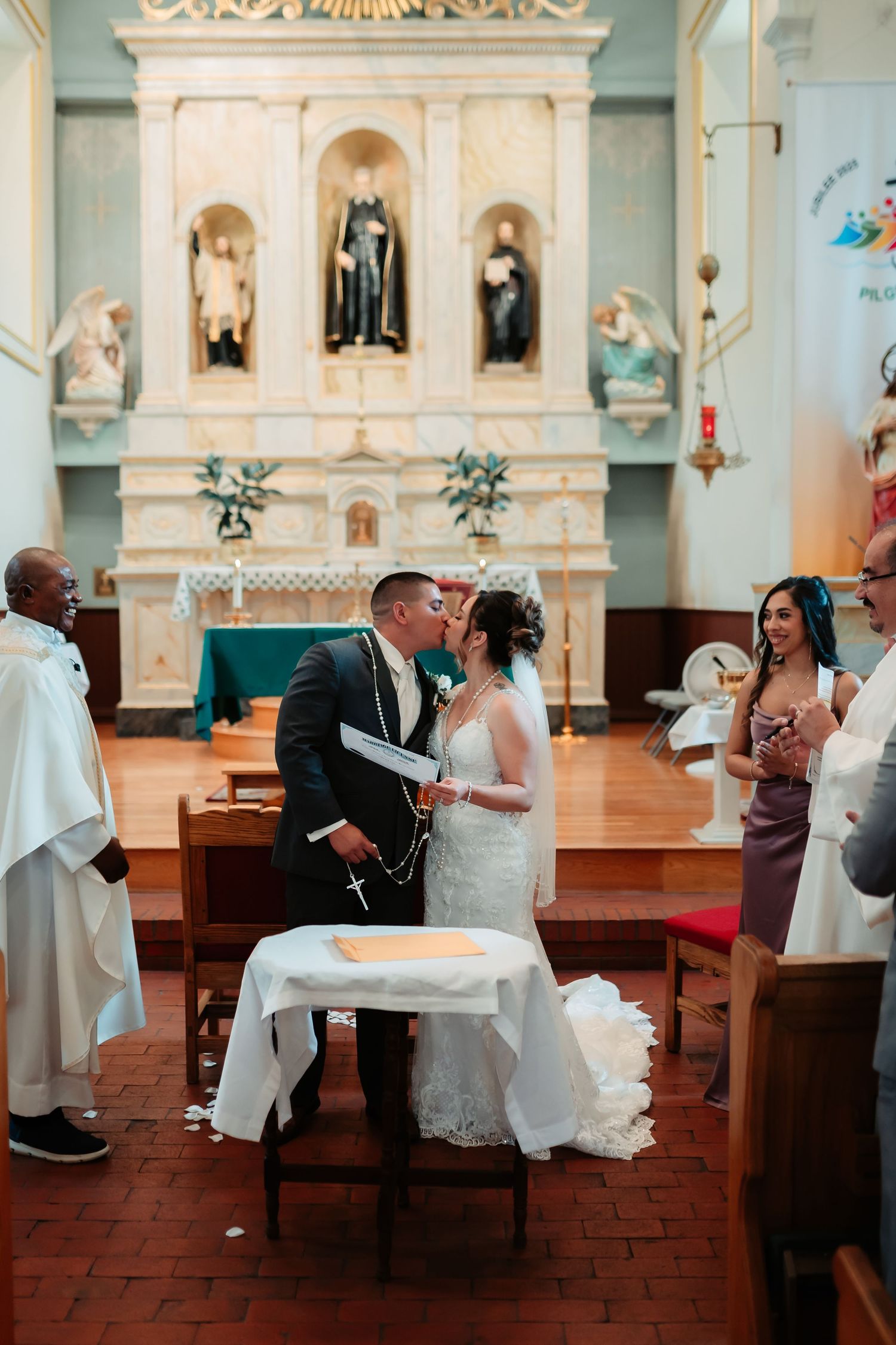 Wedding party members interacting in elegant church interior with terracotta floors.