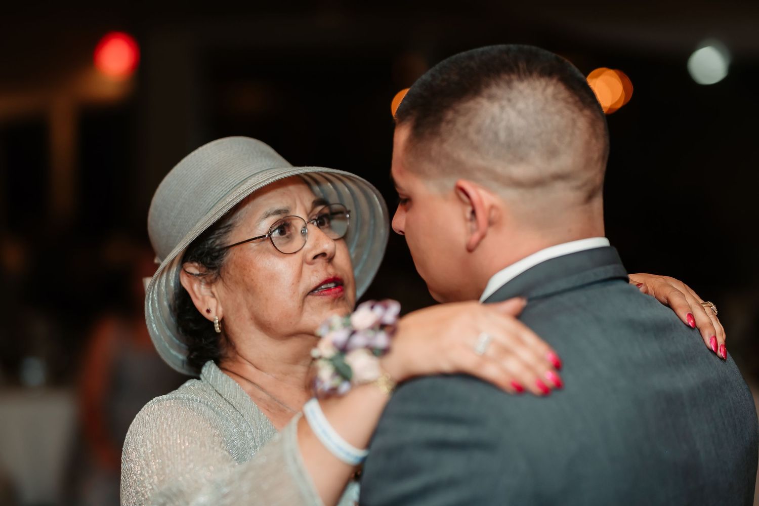 Two people share a heartfelt dance moment on the dance floor at an indoor wedding reception.