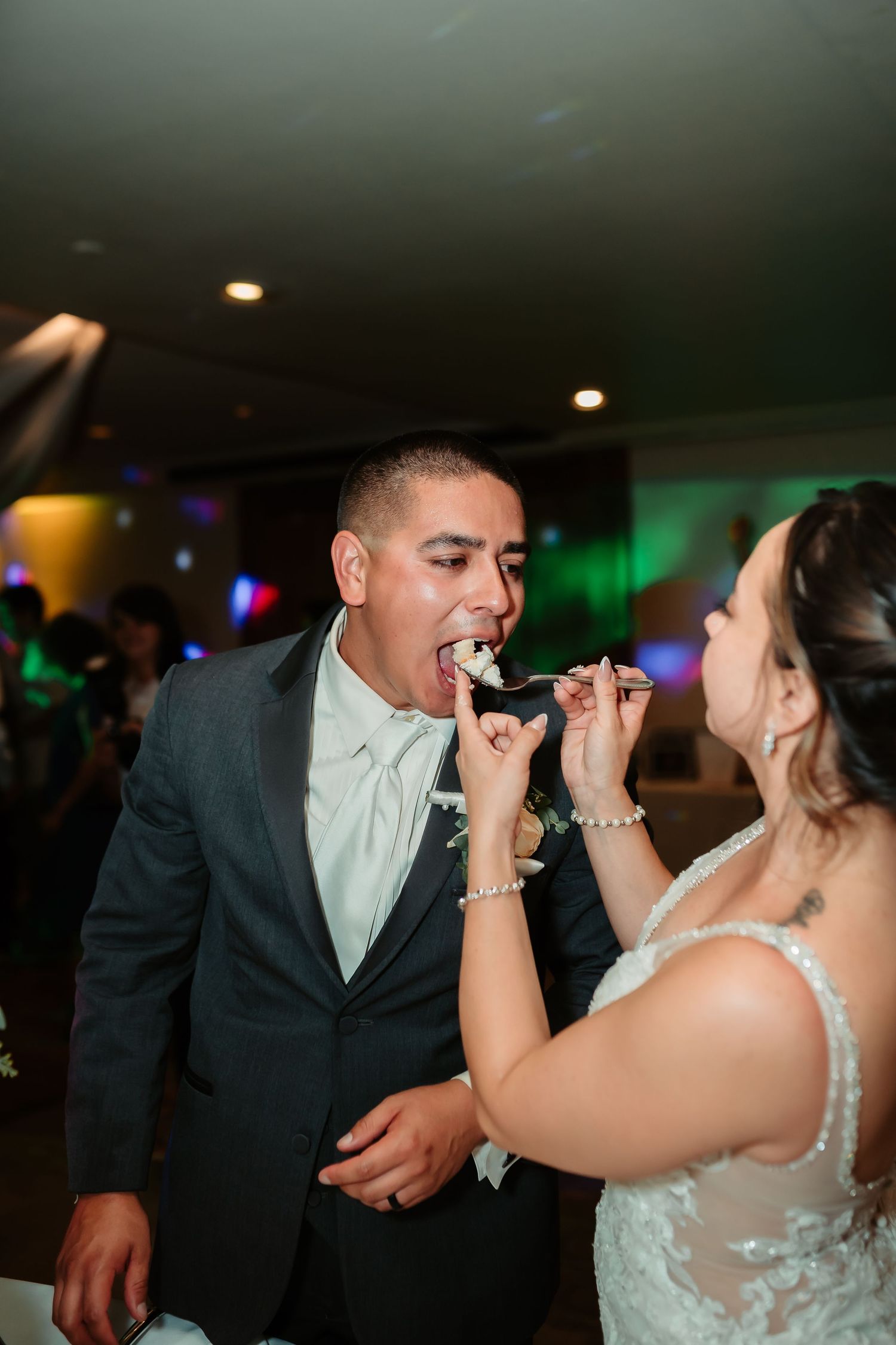 Bride and groom feed each other wedding cake in a traditional cake cutting ceremony.