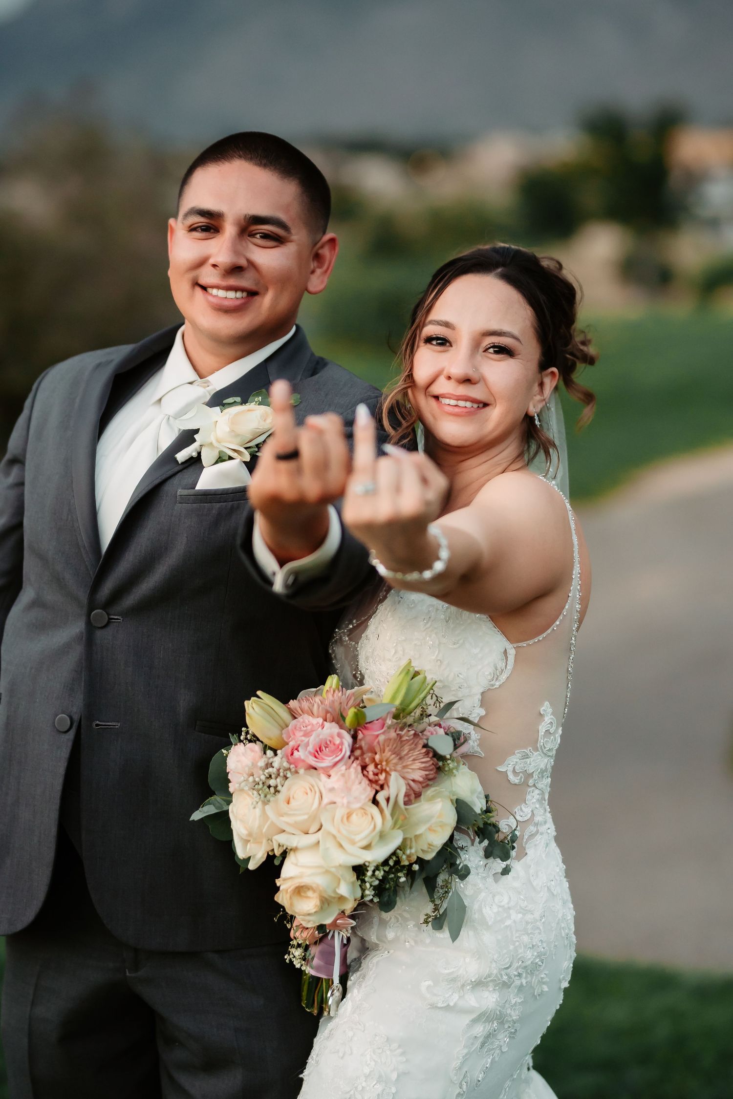 Playful wedding portraits with the bride holding her bouquet and showing off her ring.