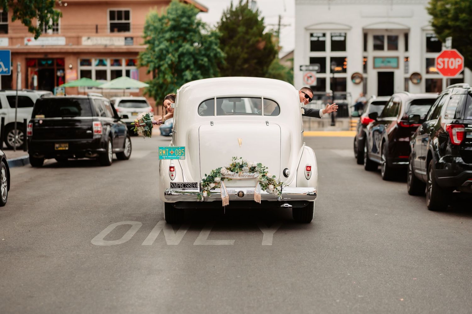 Classic wedding cars lined up along an urban street with buildings in the background.