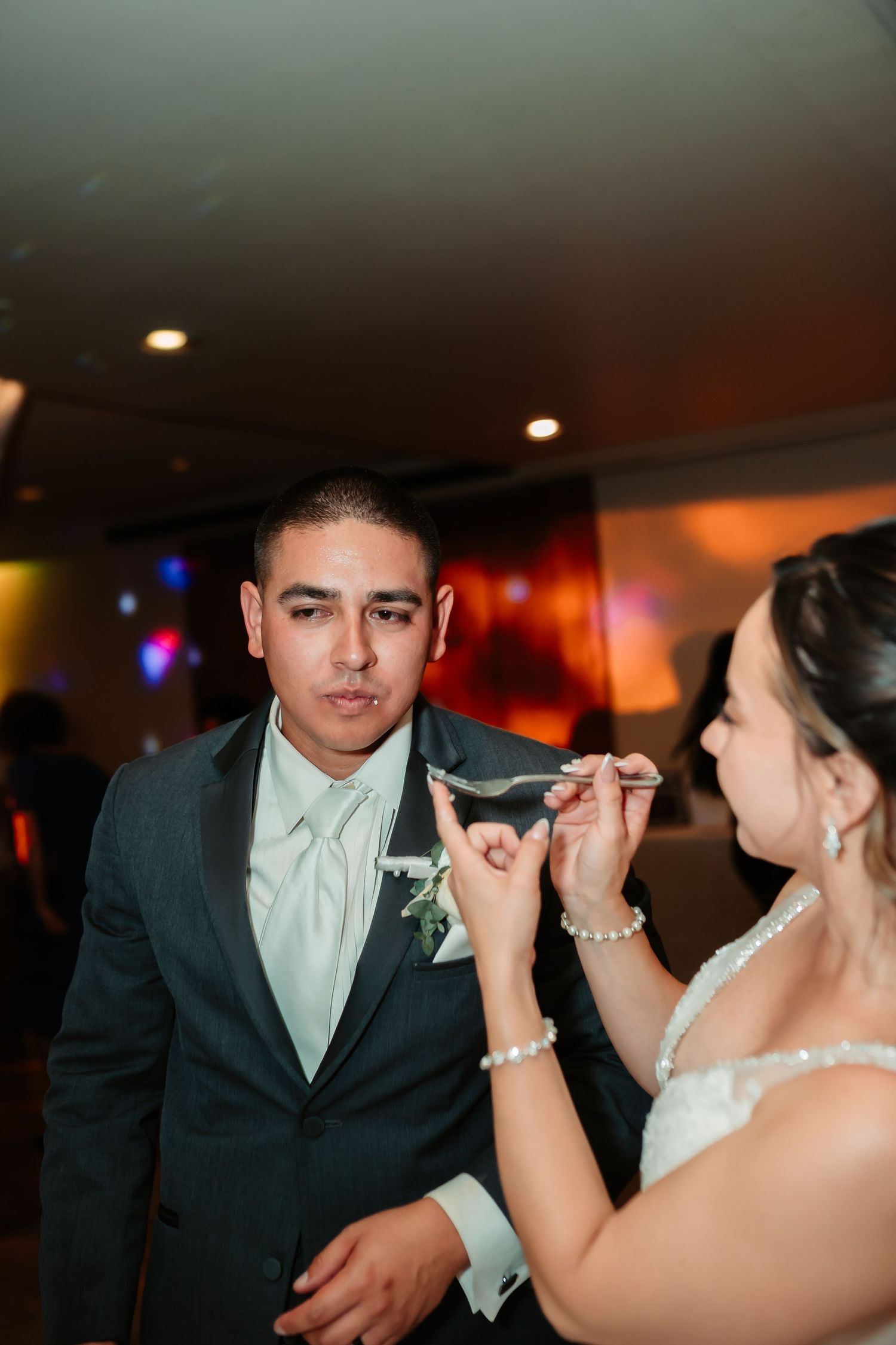 Couple participates in the wedding cake feeding tradition at their reception.