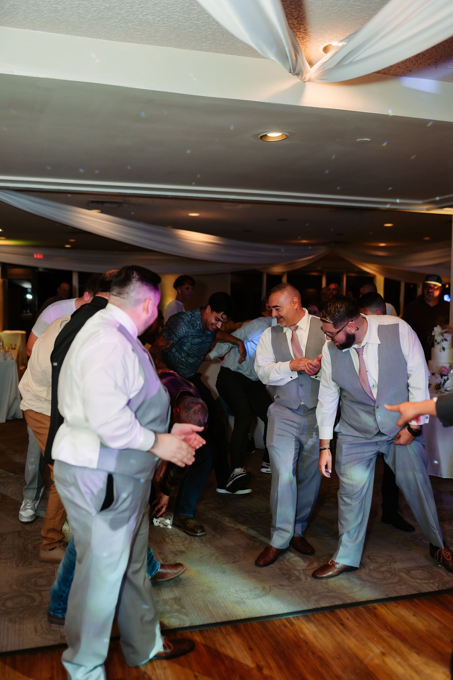 Party guests dance and have fun at a wedding reception with elegant ceiling draping.