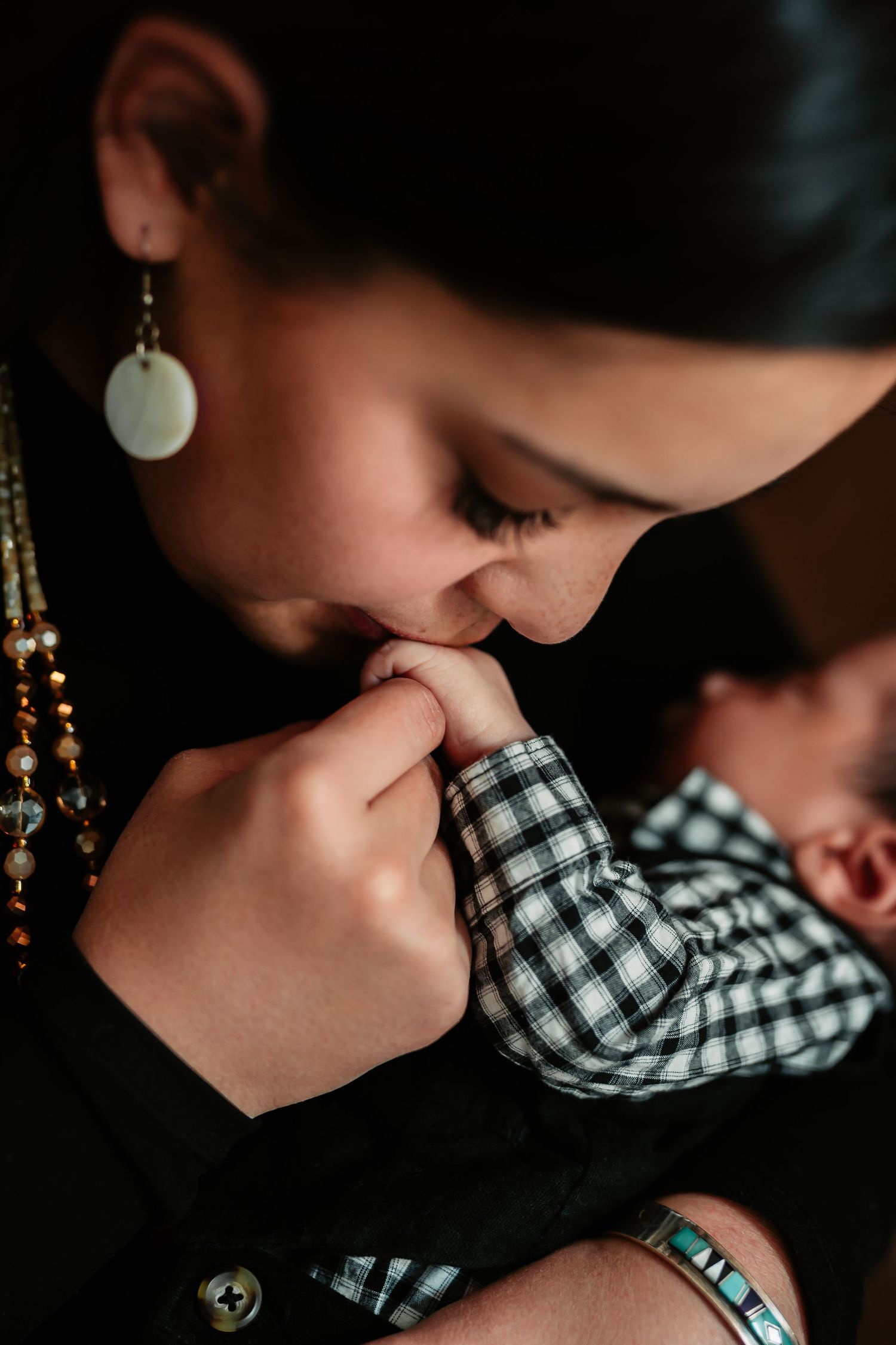 A close-up series of tender moments showing a parent kissing a baby wearing a black and white checkered shirt.