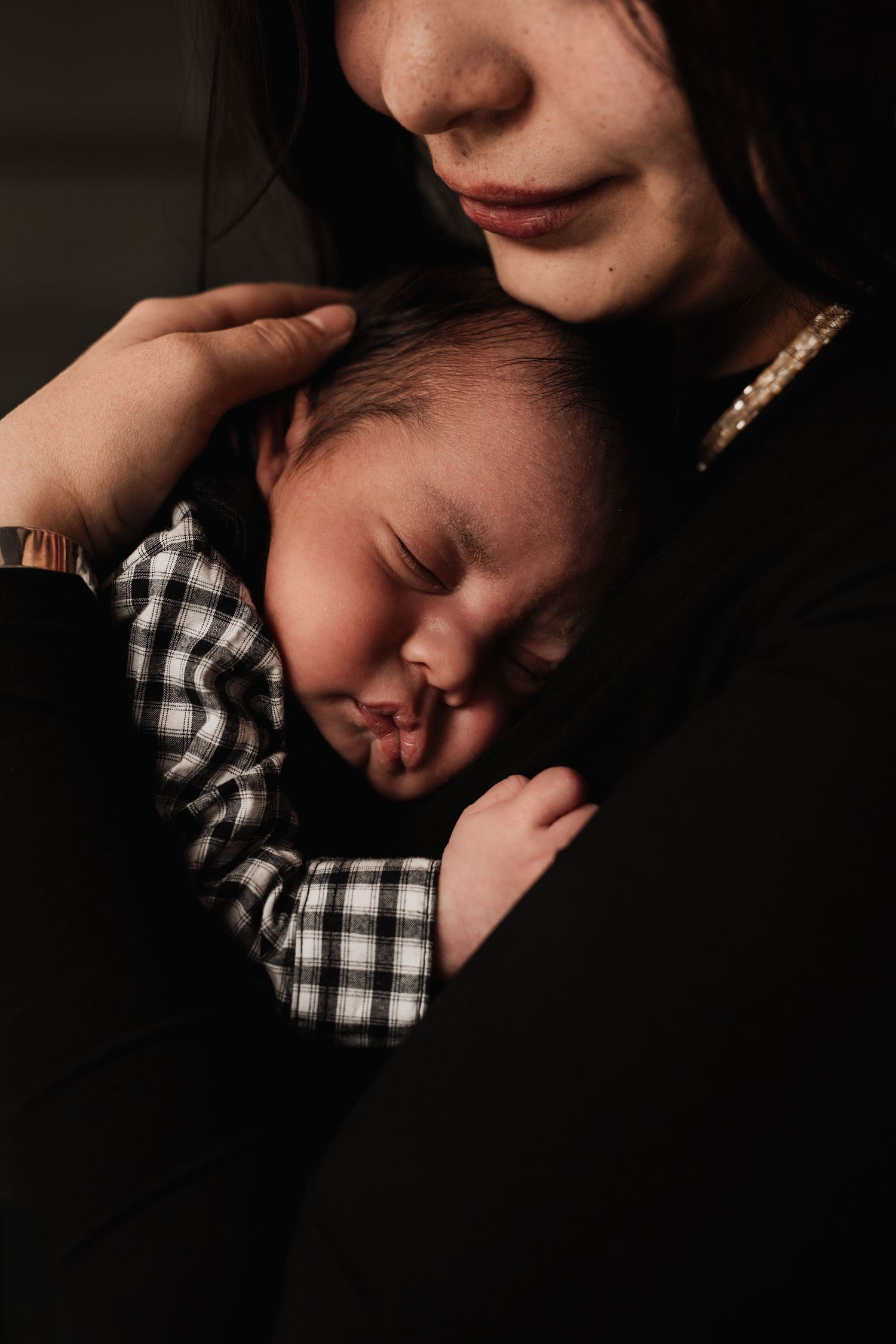 A series of intimate black and white close-up portraits showing tender moments between parent and baby.