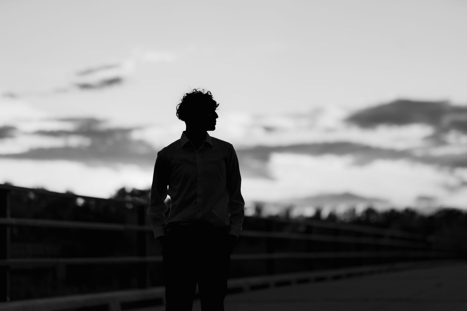 Silhouette of a person standing against a sunset sky with a dramatic cloudy backdrop.