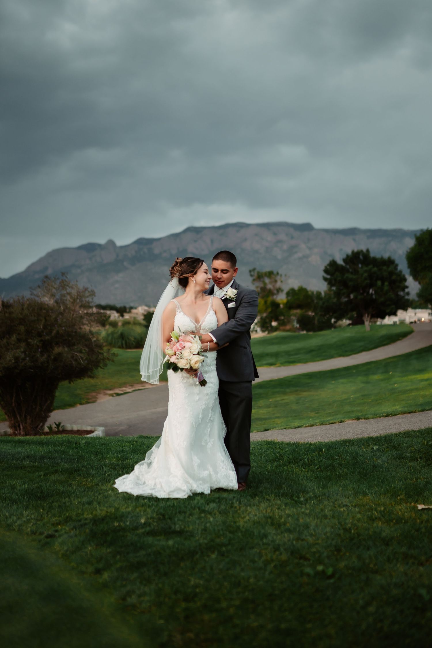 Romantic wedding photos on golf course with stormy mountain backdrop.