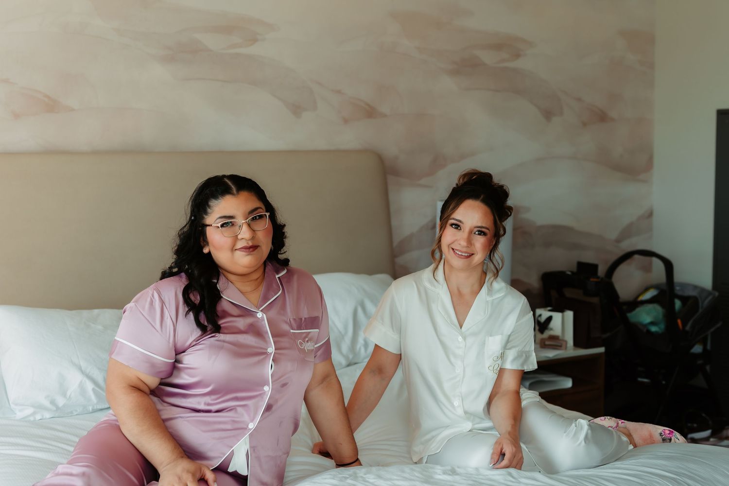 Medical staff in white and pink uniforms having a relaxed moment together on a hospital bed.