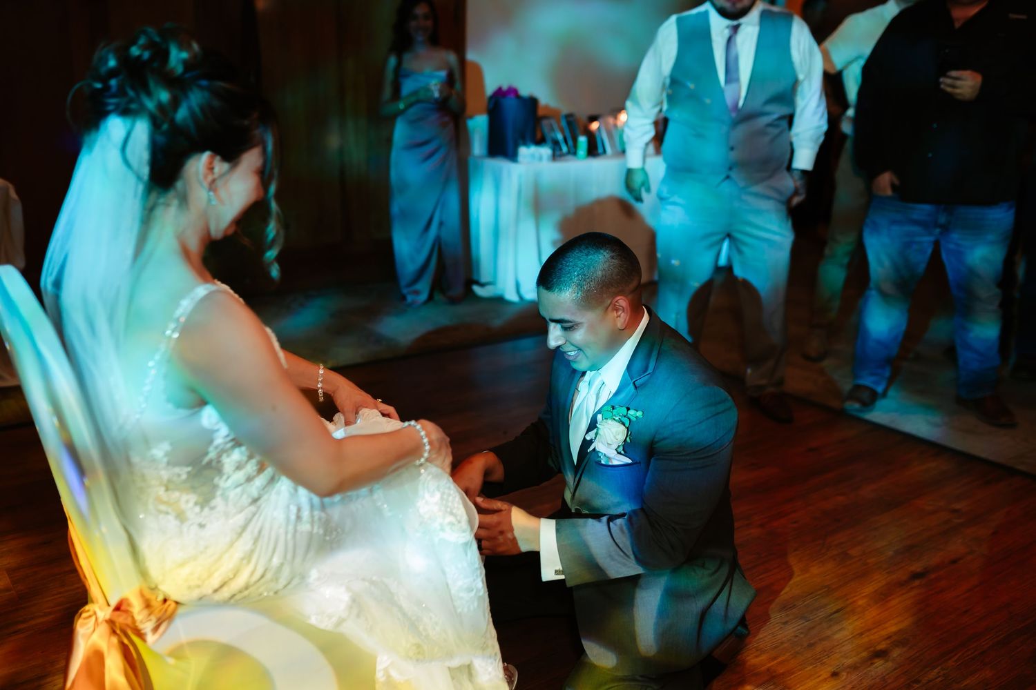 Wedding couple dances on a hardwood floor under blue ambient lighting at their reception.