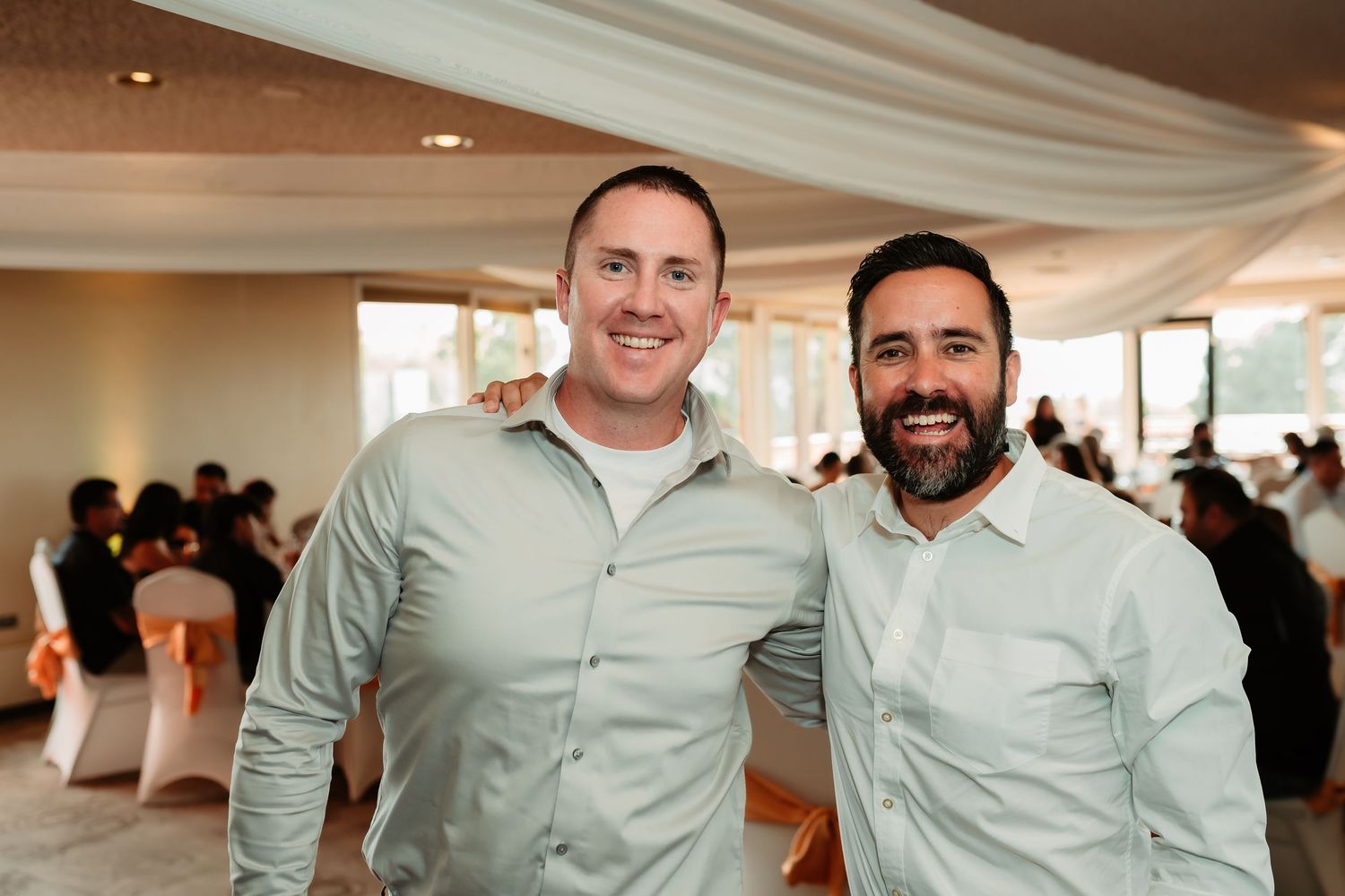 A group of people wearing matching light blue collared shirts gathered at an indoor event space with white draped ceilings.