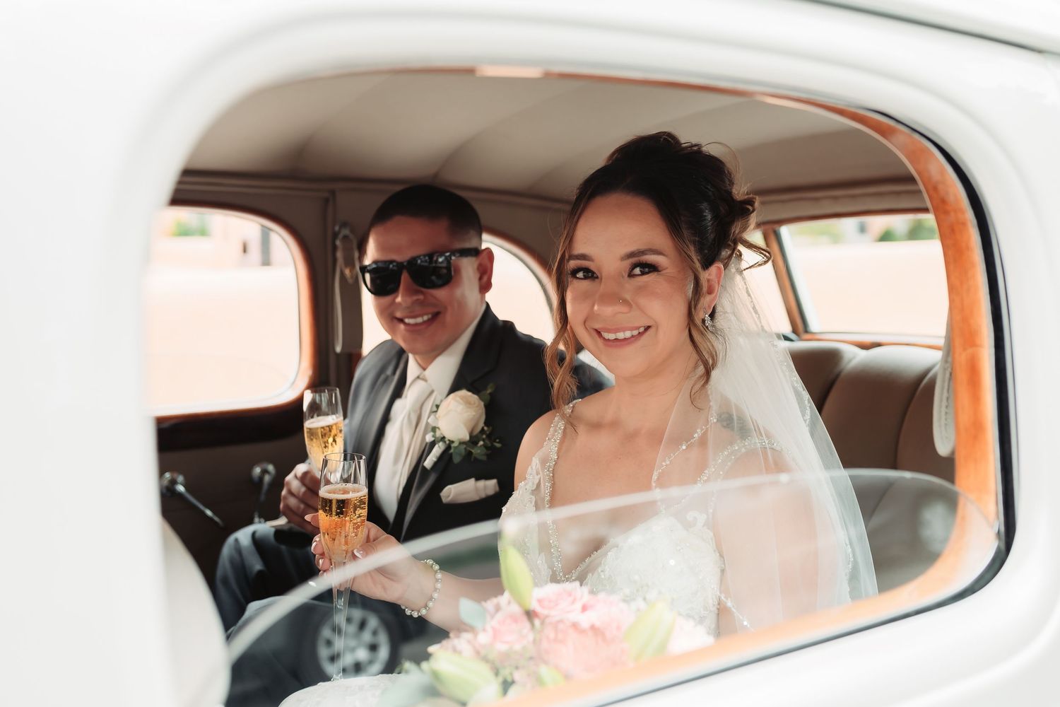 Wedding couple smiling through the windows of a classic car.