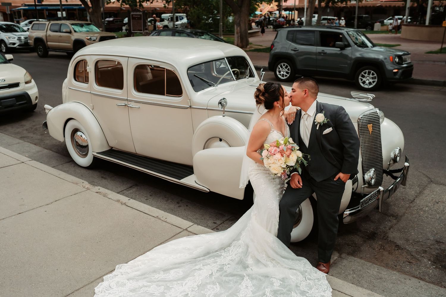 Classic vintage white car parked with wedding decorations in an outdoor setting.