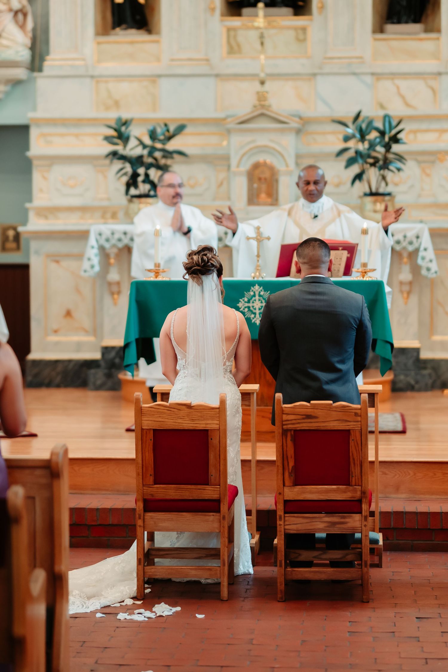 Catholic church ceremony with green altar decorations and wooden pews in a historic sanctuary.