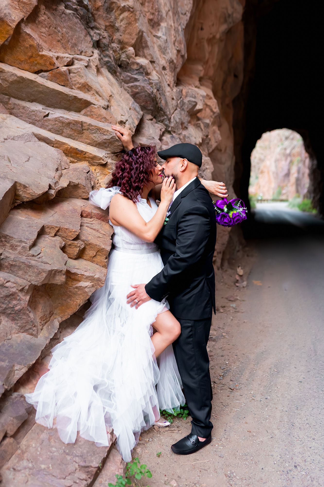 A romantic wedding couple embraces against a rustic rock canyon wall in a series of intimate poses.