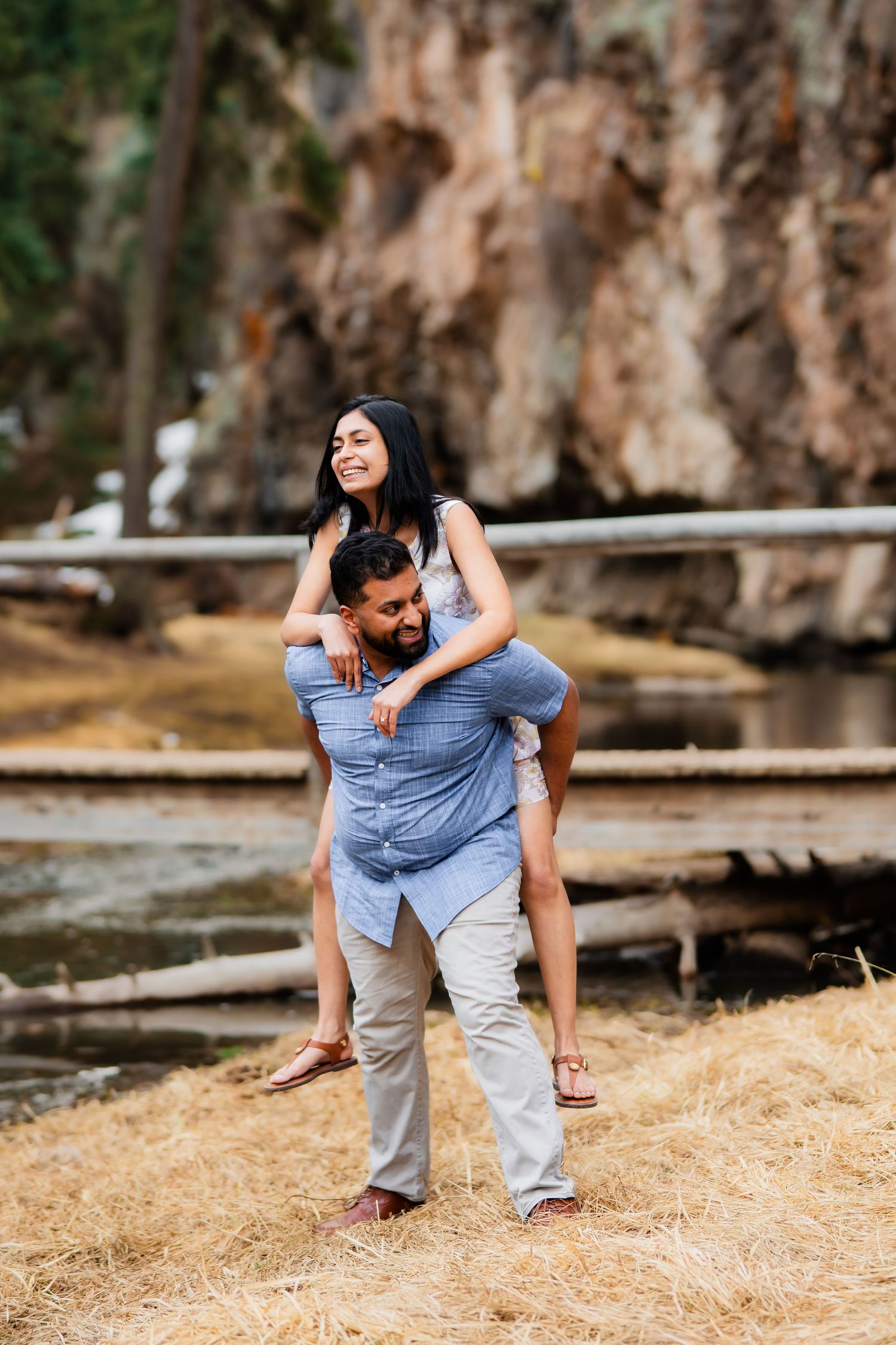 A playful piggyback ride moment captured in front of a scenic rocky landscape.