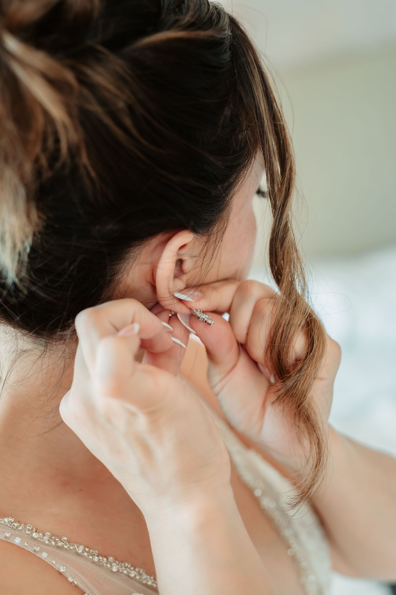 Elegant bridal jewelry being fastened around a neck before the wedding ceremony.