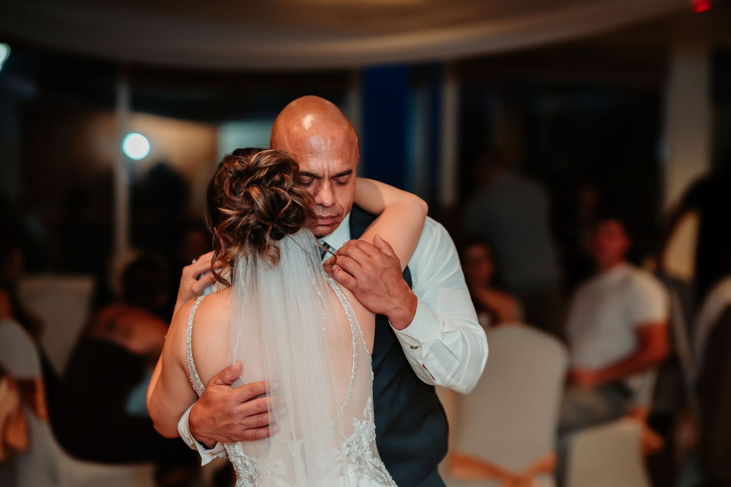 Wedding couples dancing in dimly lit reception hall with romantic lighting.