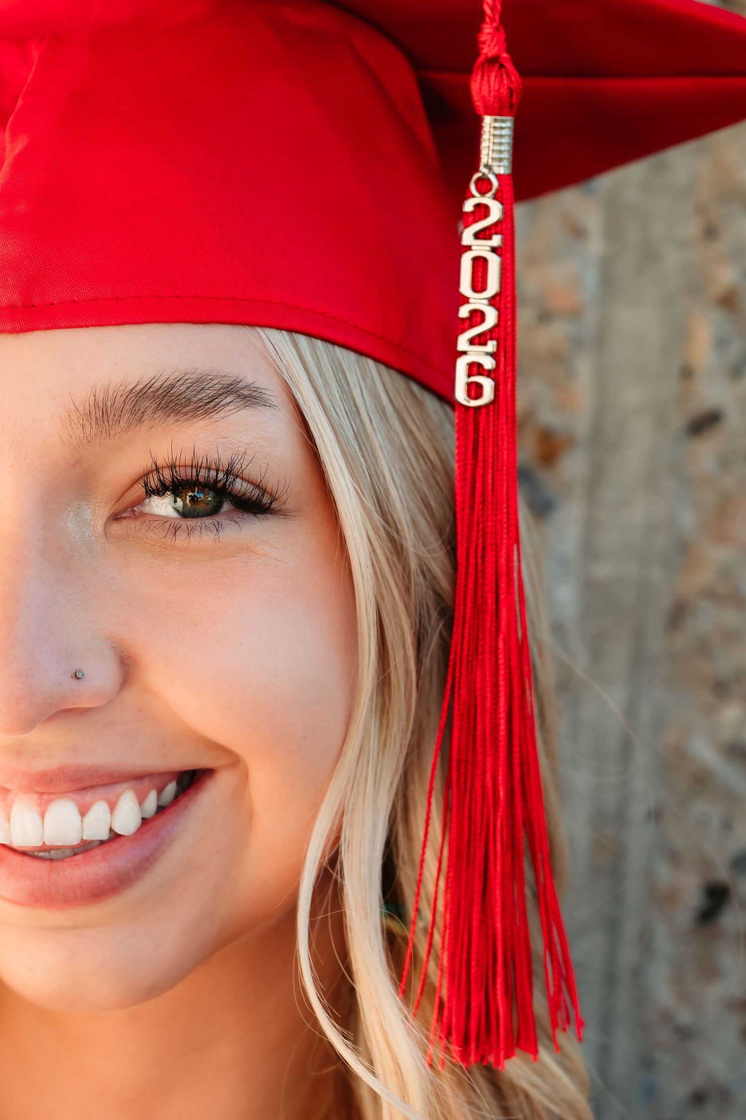 A bright red graduation cap with 2026 tassel against a blurred background.