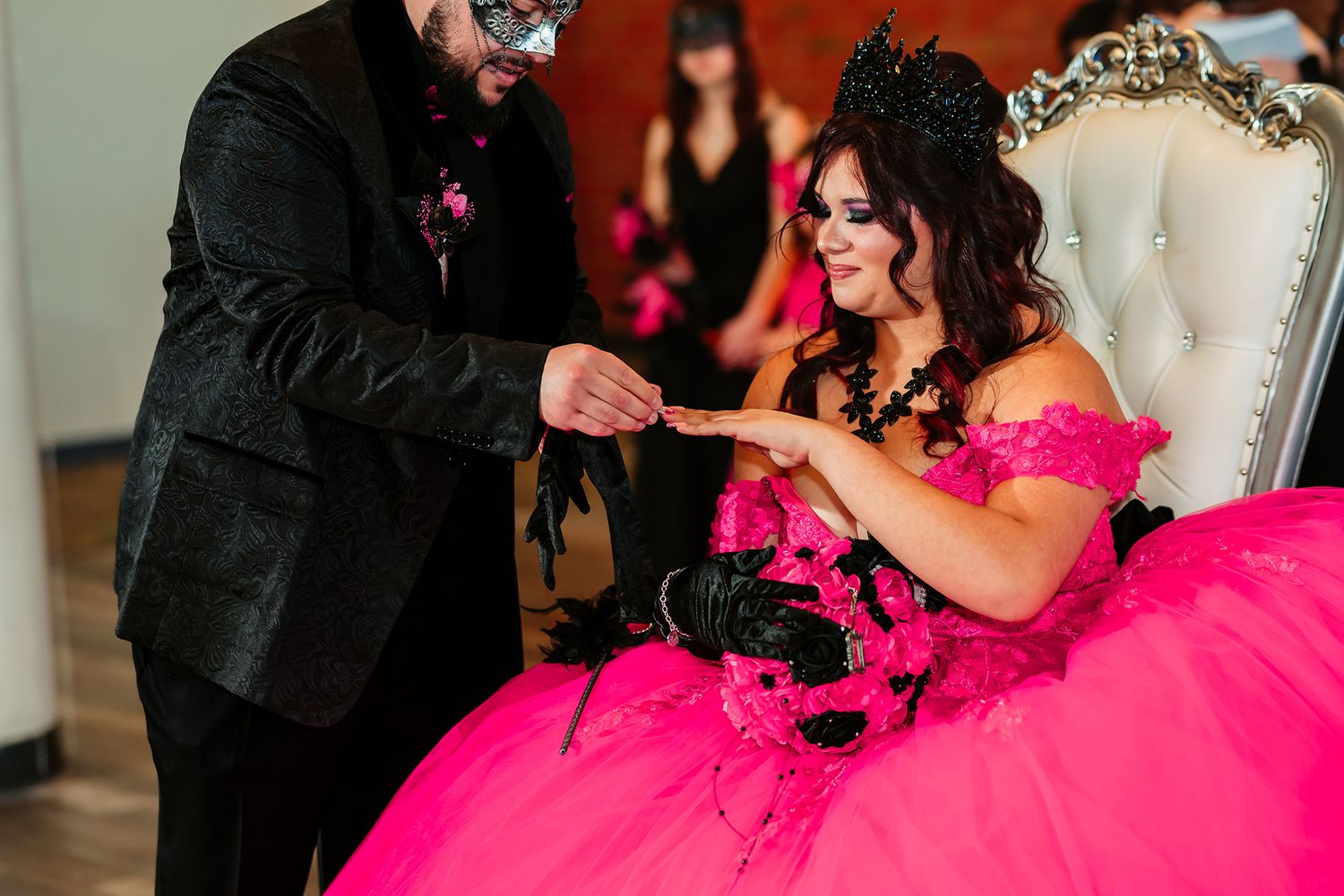 A couple shares a romantic dance moment in a ballroom with the bride wearing a vibrant hot pink ball gown.