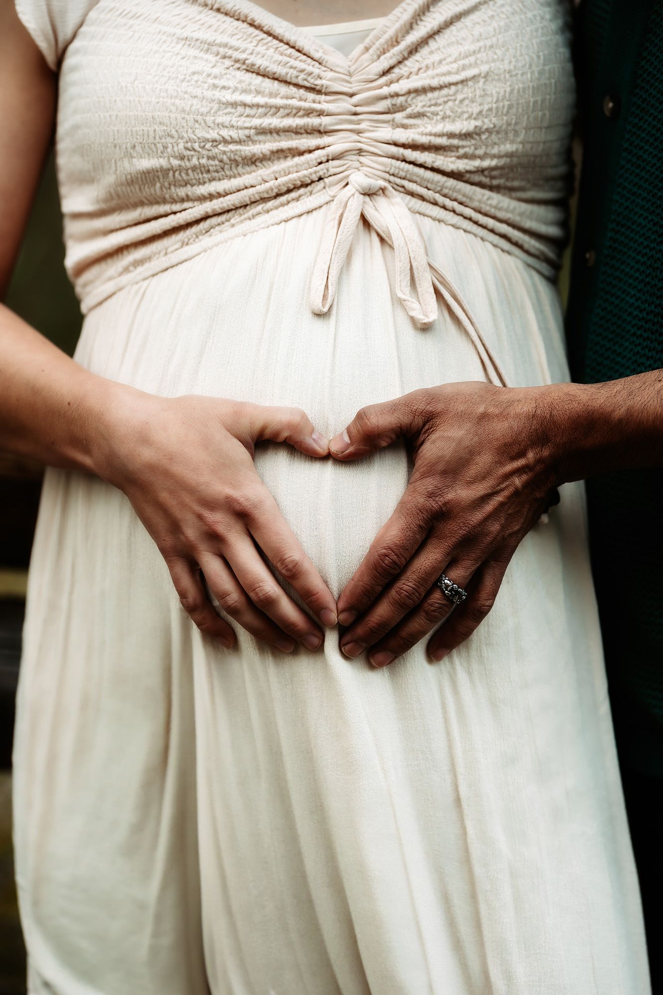 A row of bridesmaids in cream-colored dresses showing their hands clasped at their waists.