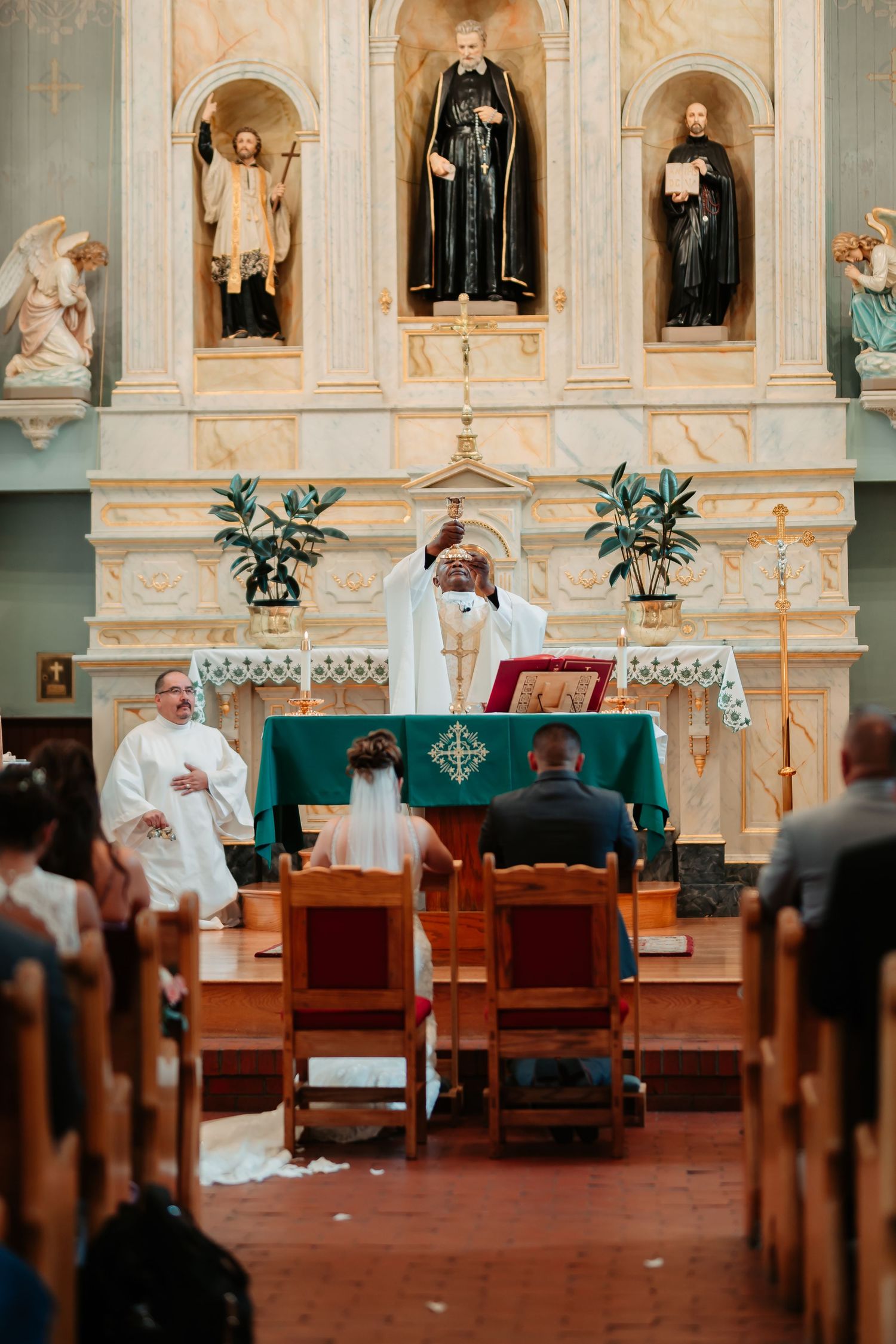 Traditional church altar with religious statues and decorative arches during a wedding ceremony.