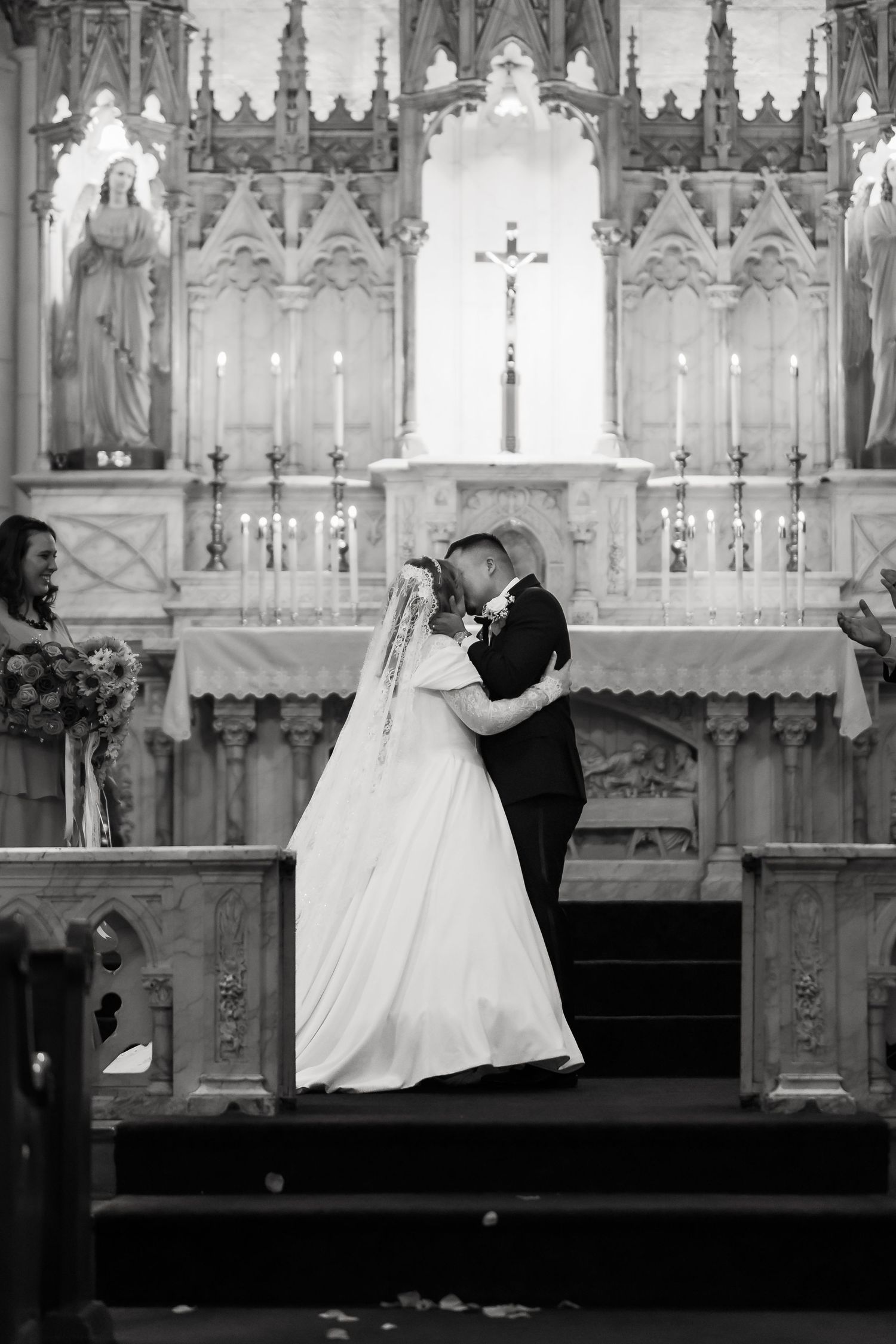 A romantic wedding ceremony takes place at the altar of a gothic church with ornate architecture and candlelight.