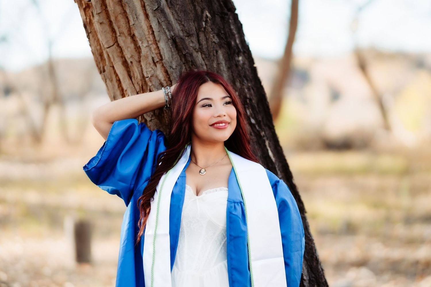 A person wearing blue and white clothing stands in front of trees in a park-like setting.