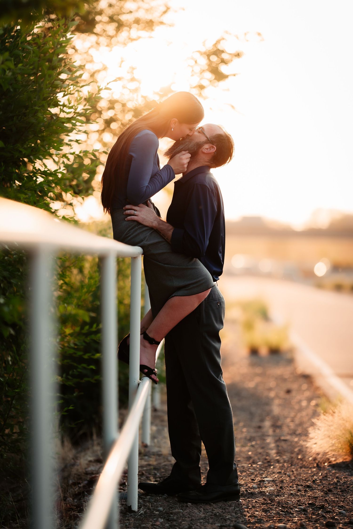 A romantic couple embraces against a glowing sunset backdrop along a railing in a series of silhouetted photos.