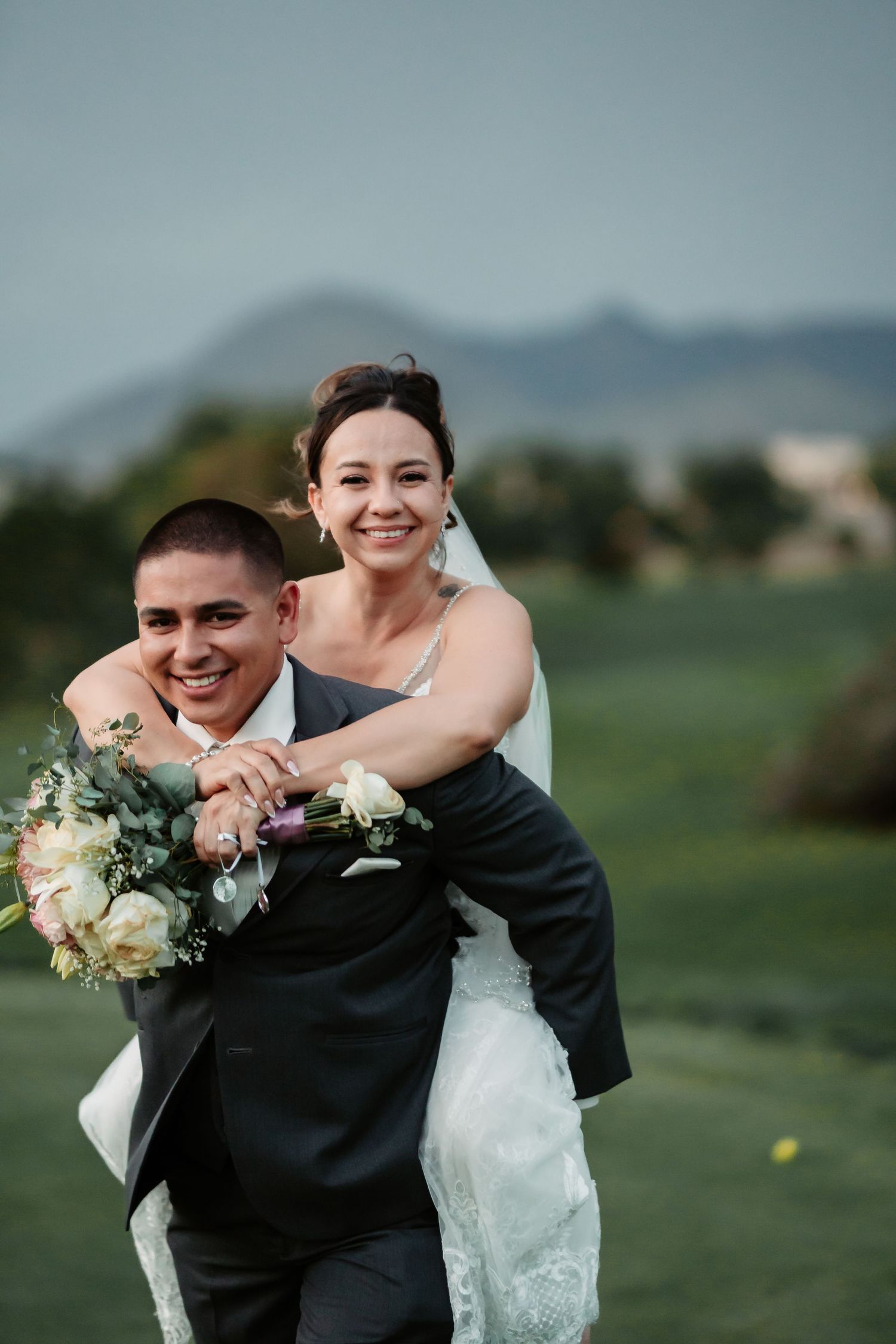 Playful wedding moment captured on a golf course with mountains in the distance.