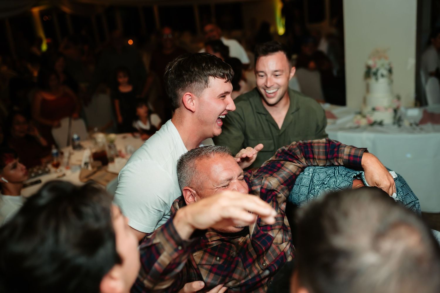 Guests participating in an energetic dance move during a lively wedding reception celebration.