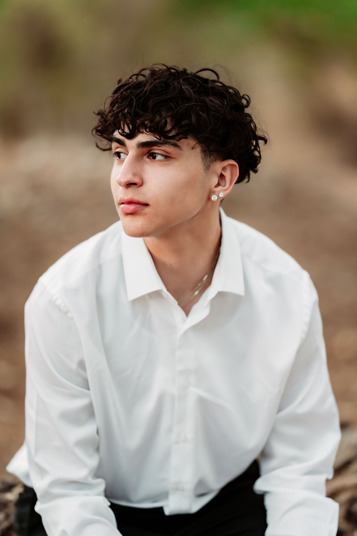 Portrait in white button-down shirt against natural outdoor background.